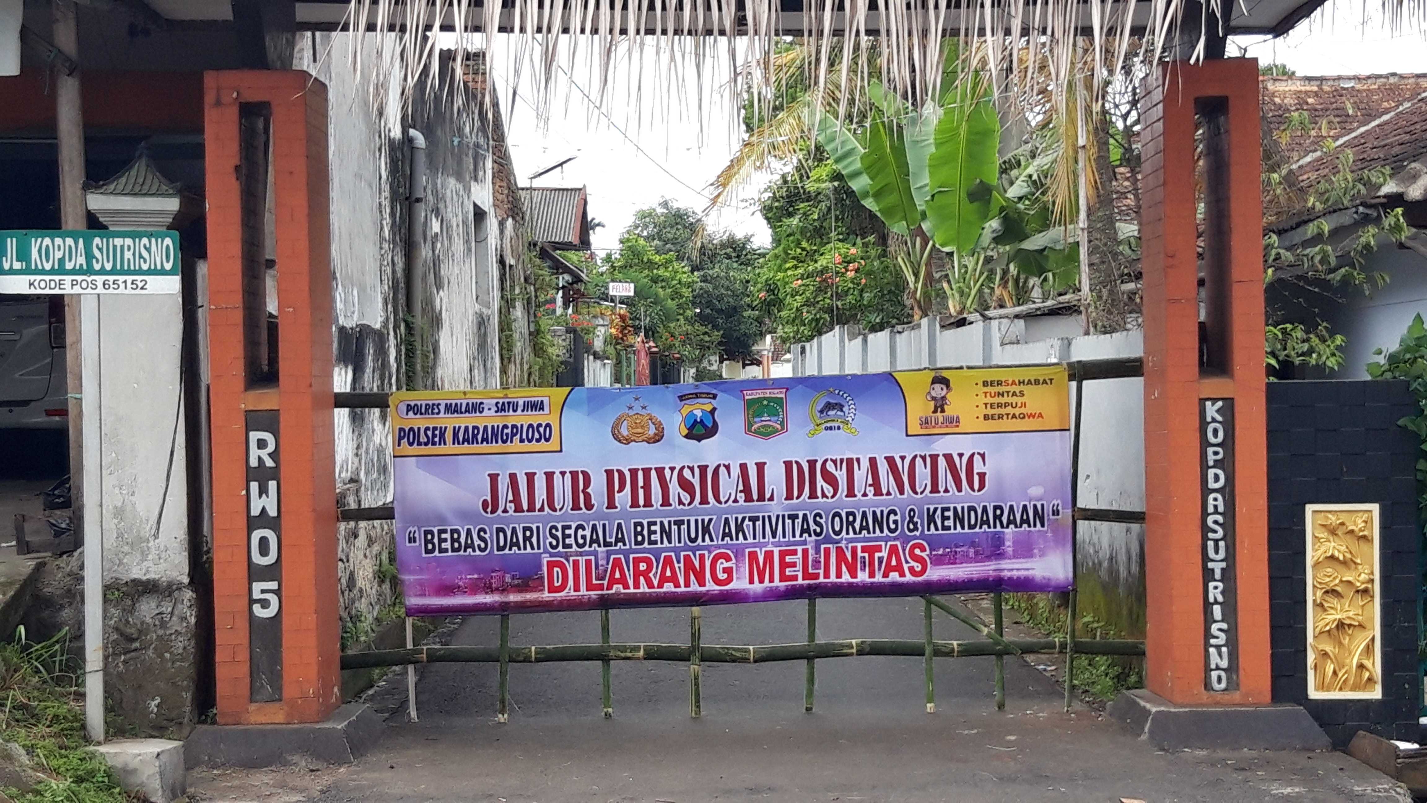 Warga di Jalan Kopda Sutrisno, Desa Girimoyo, Kecamatan Karangploso, Kabupaten Malang, Jawa Timur, menutup jalan untuk membatasi kontak oran