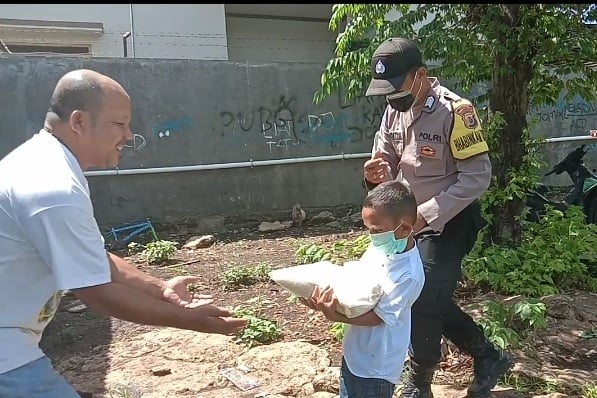 Bocah menyerahkan bantuan ke warga
