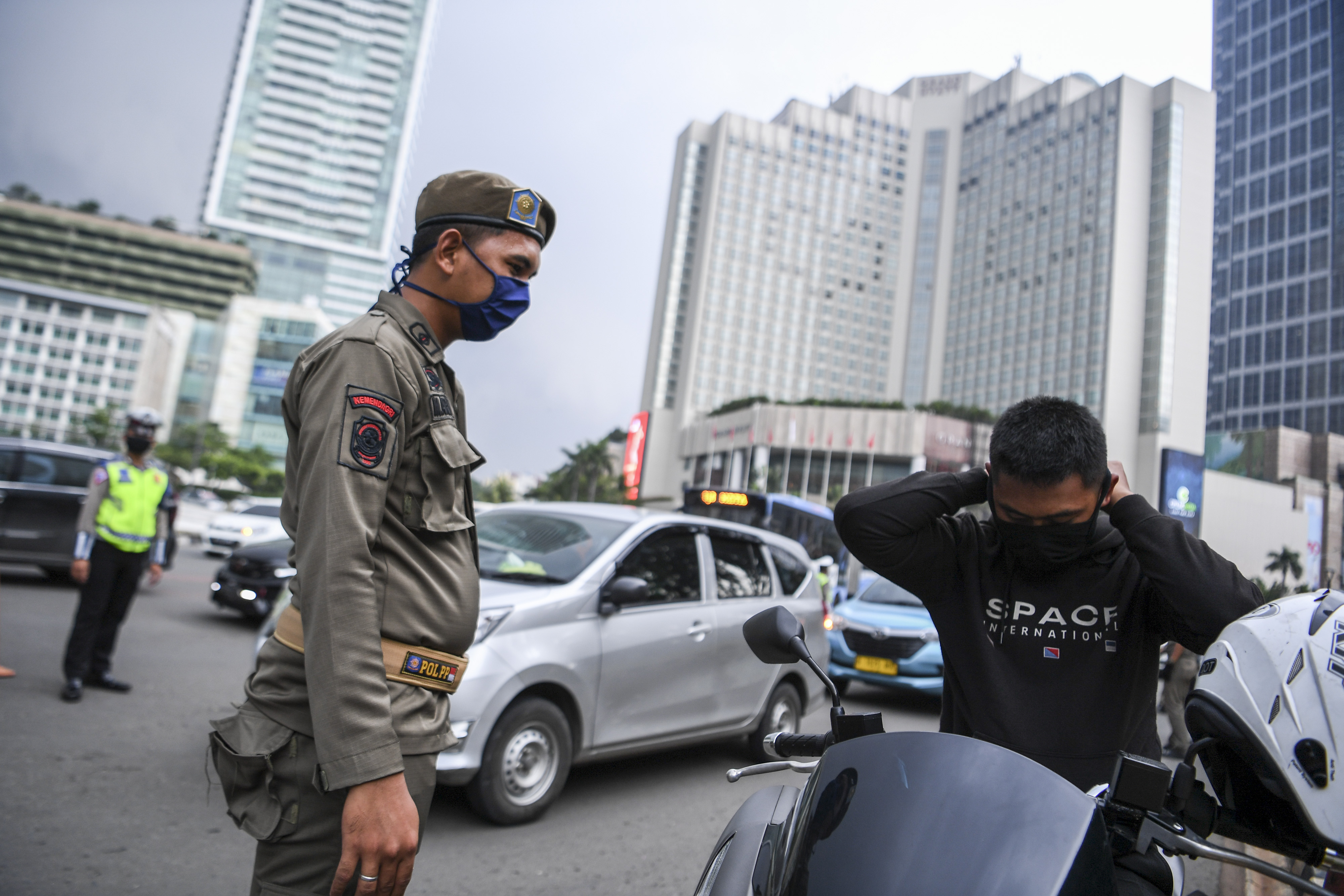 Satpol PP meminta pengendara motor mengenakan masker saat pemeriksaan kepatuhan PSBB di kawasan Bundaran HI, Jakarta, Senin (13/4).