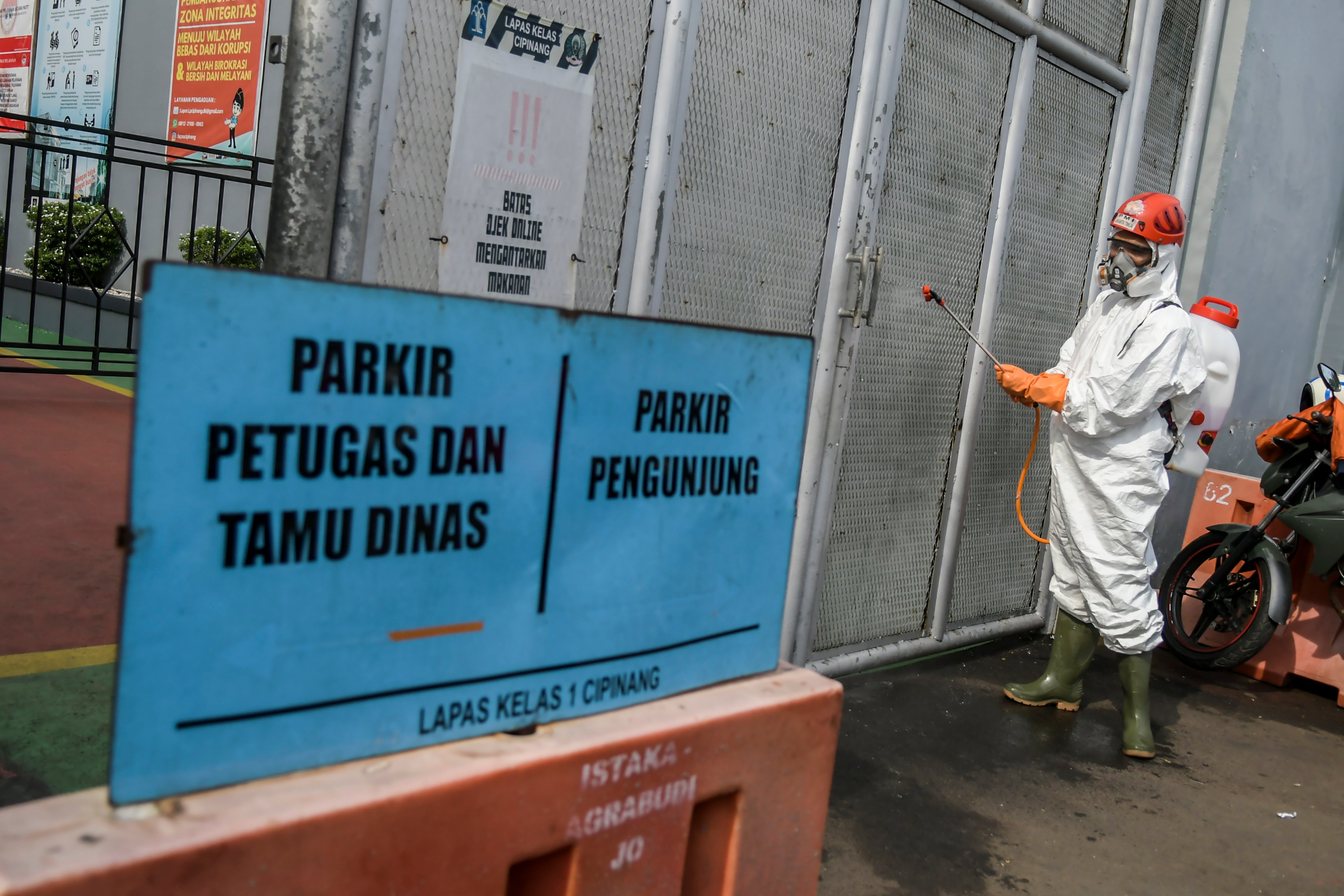 Petugas PMI menyemprotkan cairan disinfektan di pintu Lembaga Pemasyarakatan Kelas 1 Cipinang, Jakarta, Jumat (20/3).