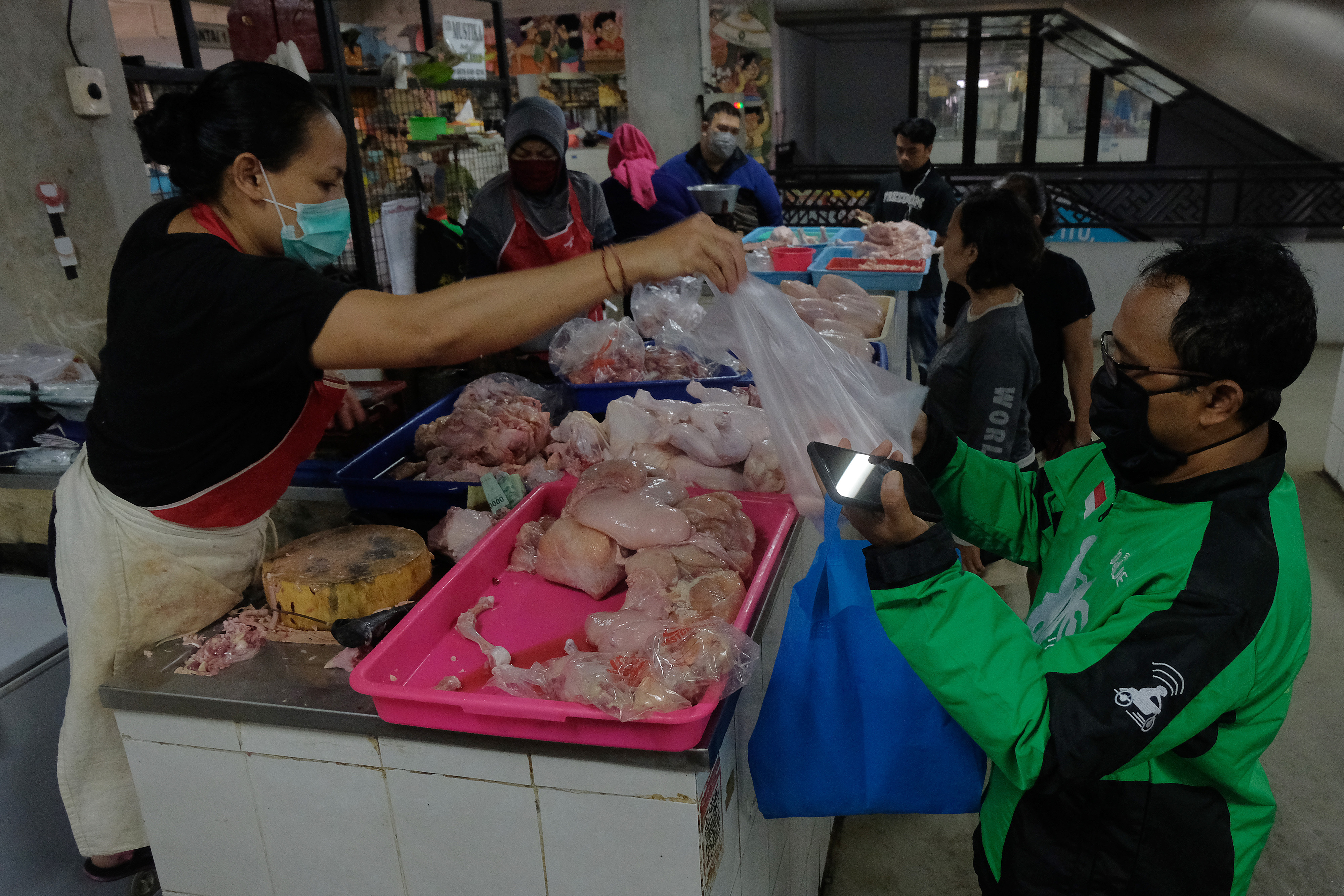  Pedagang daging ayam di Pasar Badung, Bali melayani pembeli melalui jasa online lewat pengemudi ojek daring.