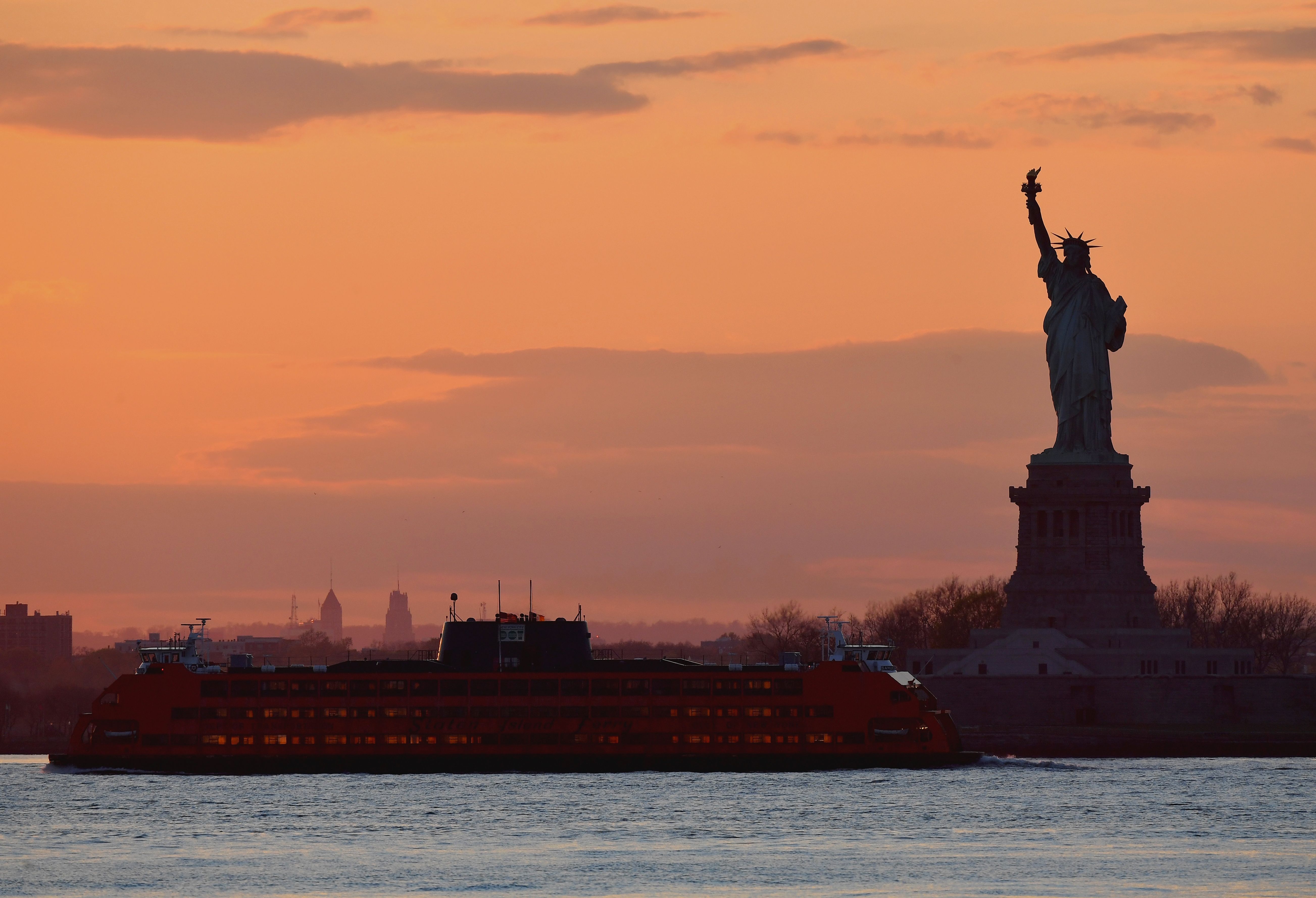 Staten Island Ferry lewat di depan Patung Liberty saat matahari terbenam di tengah pandemi covid-19 di New York, AS, Selasa (28/4).