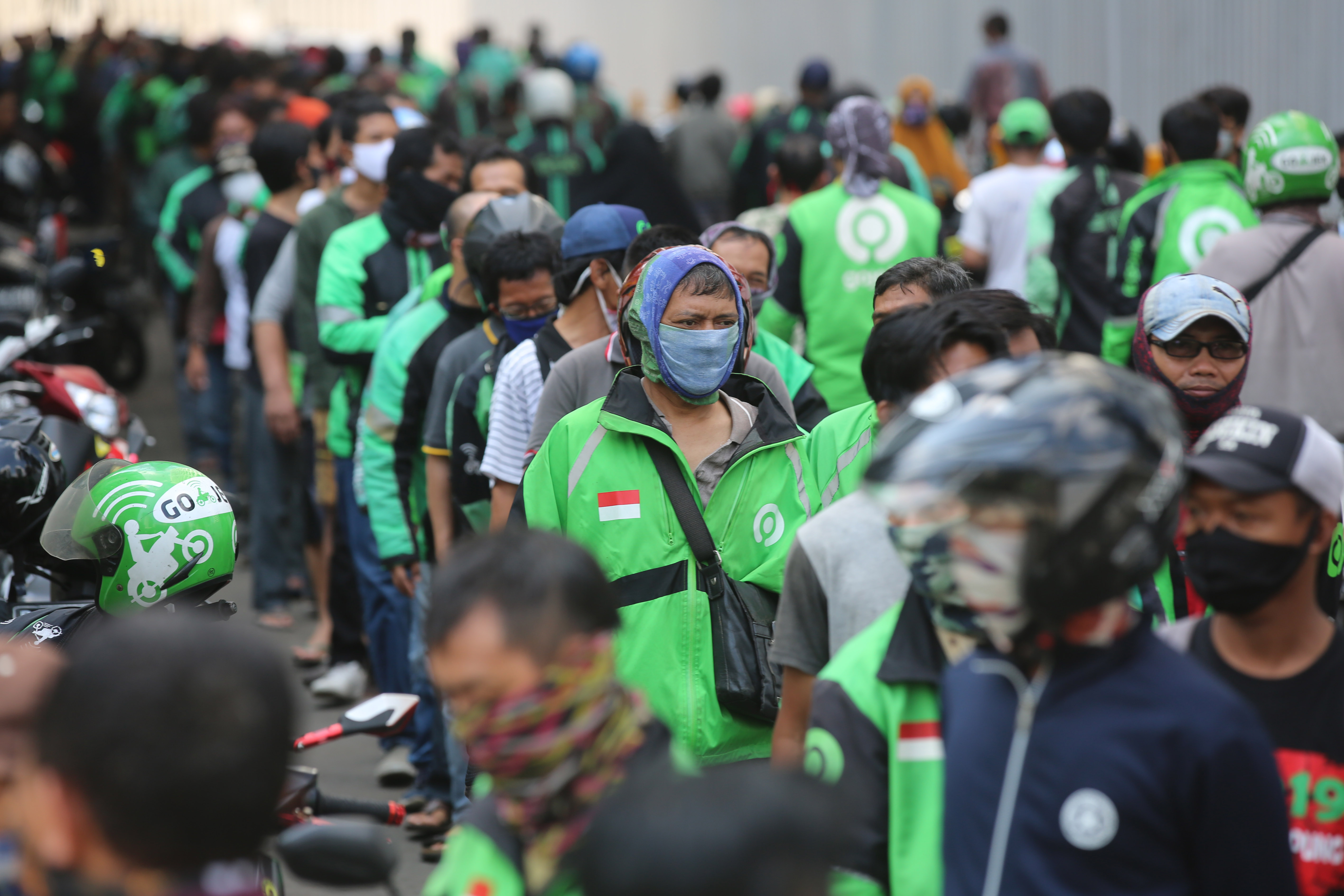 Ojek daring bersama warga antre mendapatkan makan siang yang dibagikan salah satu perusahaan di kawasan Sudirman, Jakarta, Kamis (16/4).