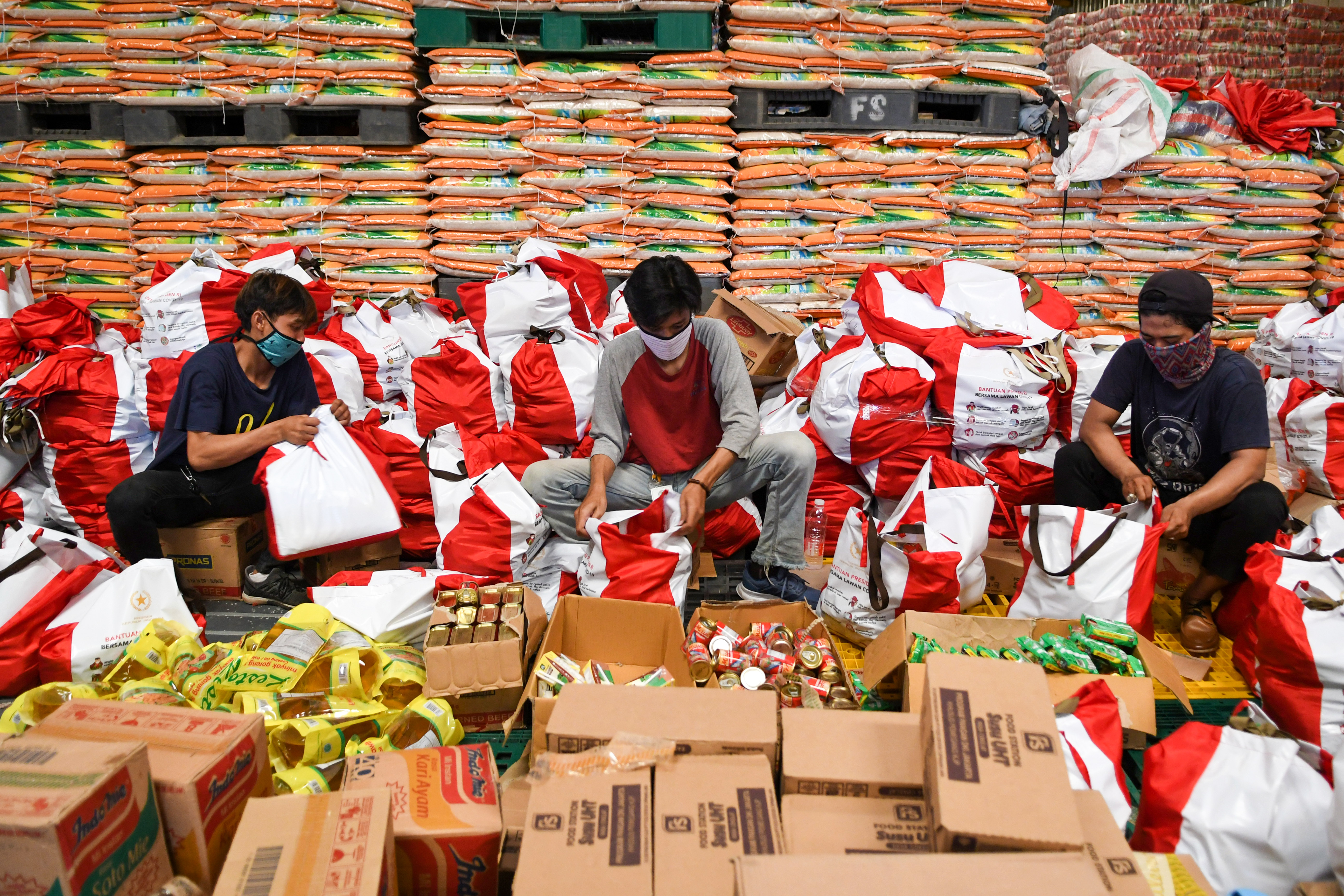 Pekerja mengemas paket bantuan sosial (bansos) di Gudang Food Station Cipinang, Jakarta.