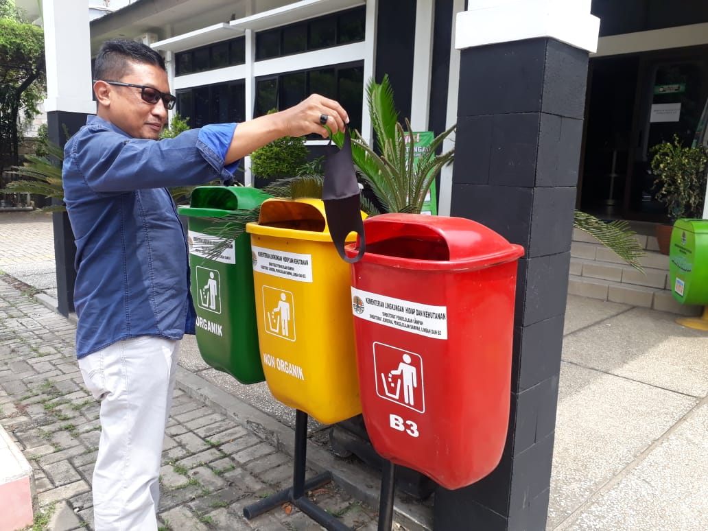 Warga membuang masker bekas dipakainya ke tempat sampah khusus limbah B3.