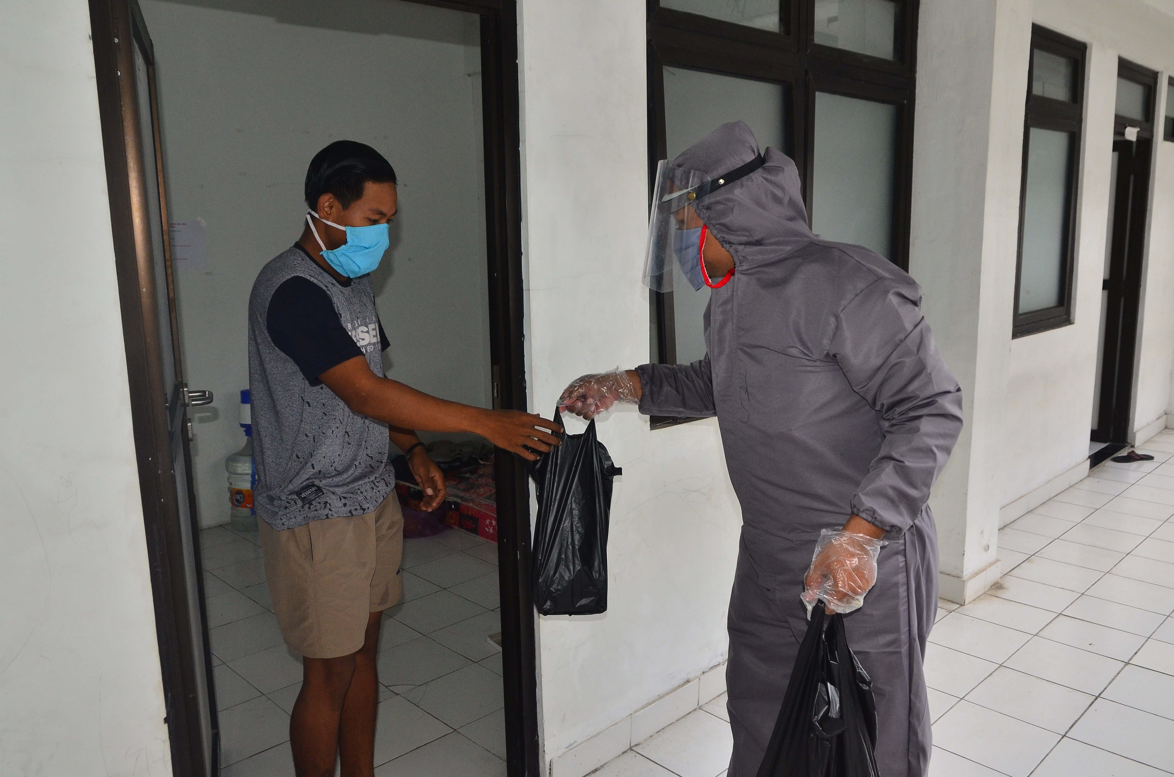 Petugas membagikan makanan kepada Orang Dalam Pemantauan (ODP) covid-19 yang dikarantina di Rusunawa Bakalan Krapyak, Kudus, Jateng, Rabu.