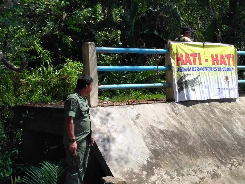 Petugas Balai Besar Konservasi Sumber Daya Alam (BBKSDA) Riau memasang poster peringatan kemungkinan serangan buaya muara (Crocodylus  poros