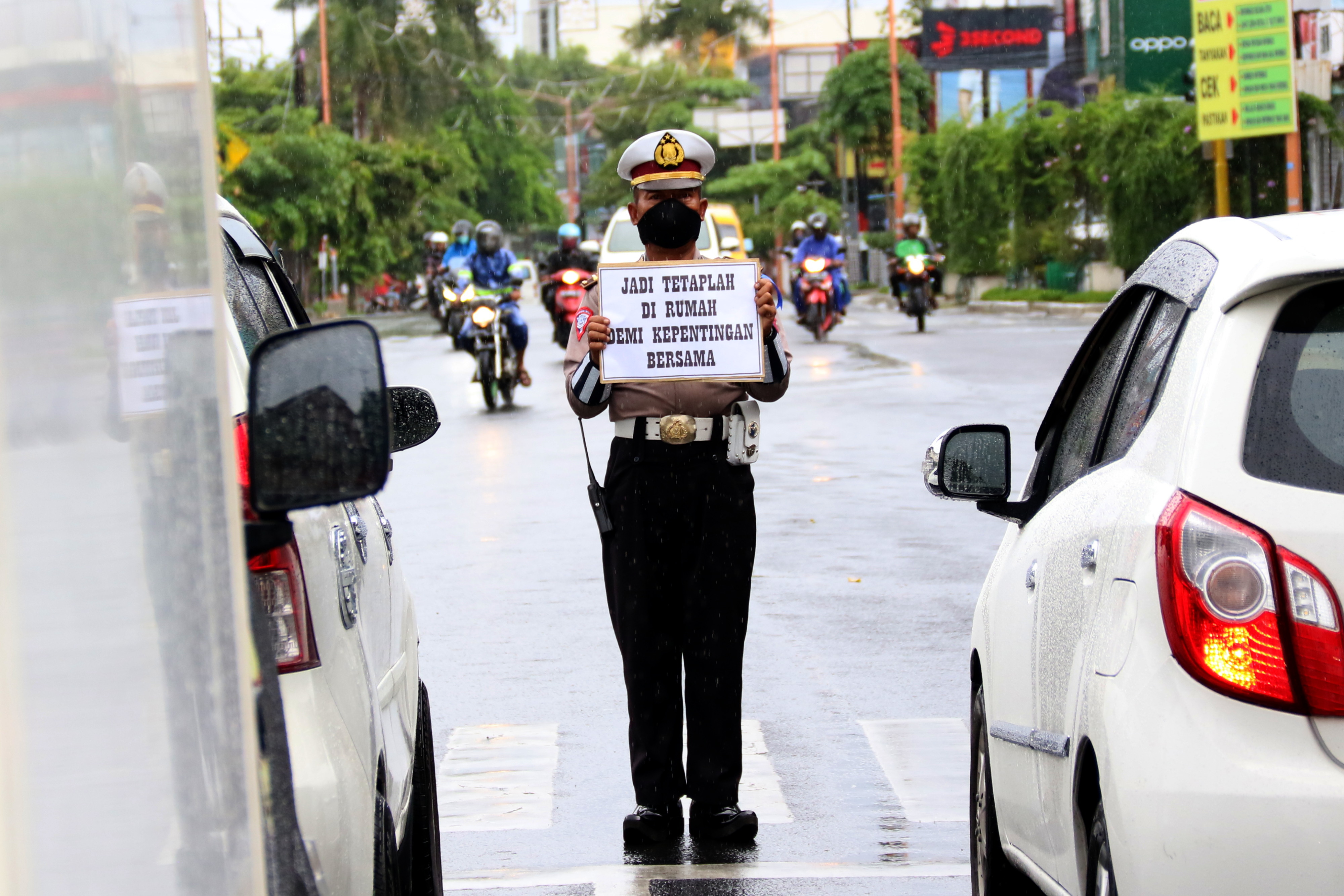 Anggota polisi menunjukkan tulisan imbauan agar warga tetap di rumah saja di Perliman, Banyuwangi, pada 6/4/2020