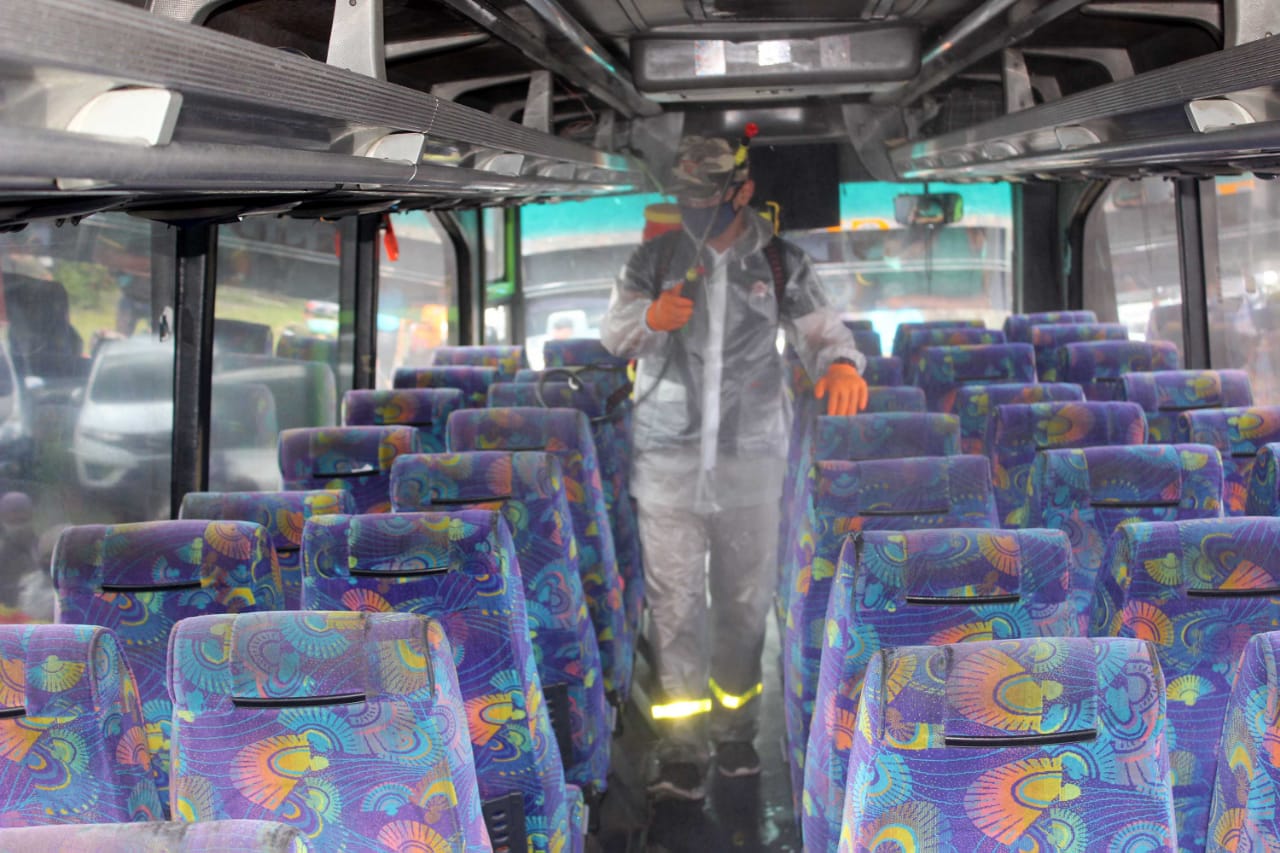 Petugas check point sedang menyemprotkan disinfektan di dalam bus antarkota di Kota Malang