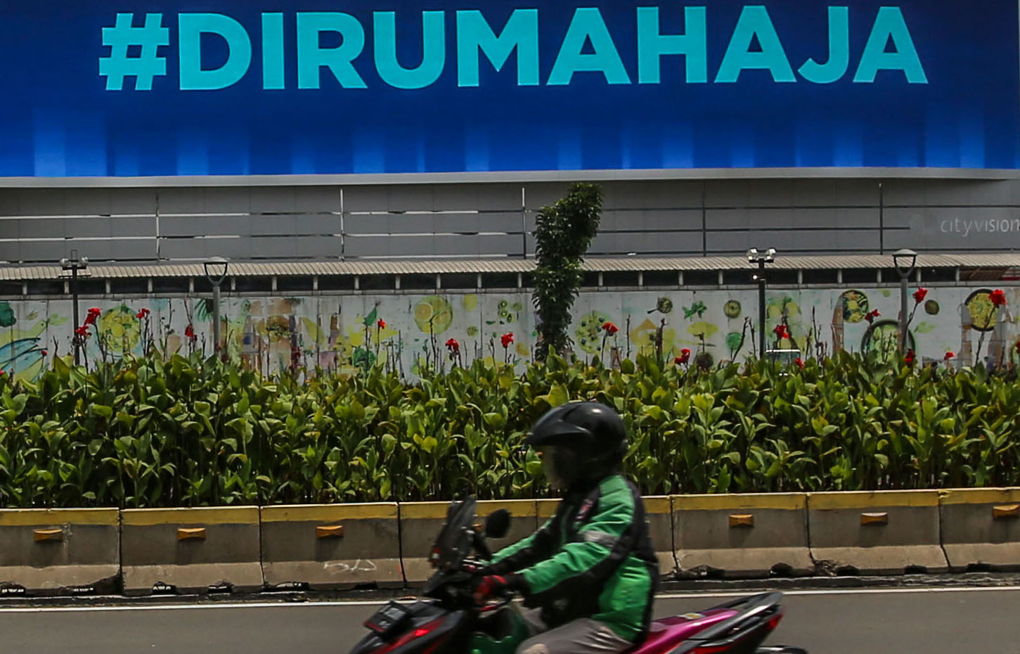Pengendara melintasi papan pengumuman terkait pencegahan covid-19 di Jakarta