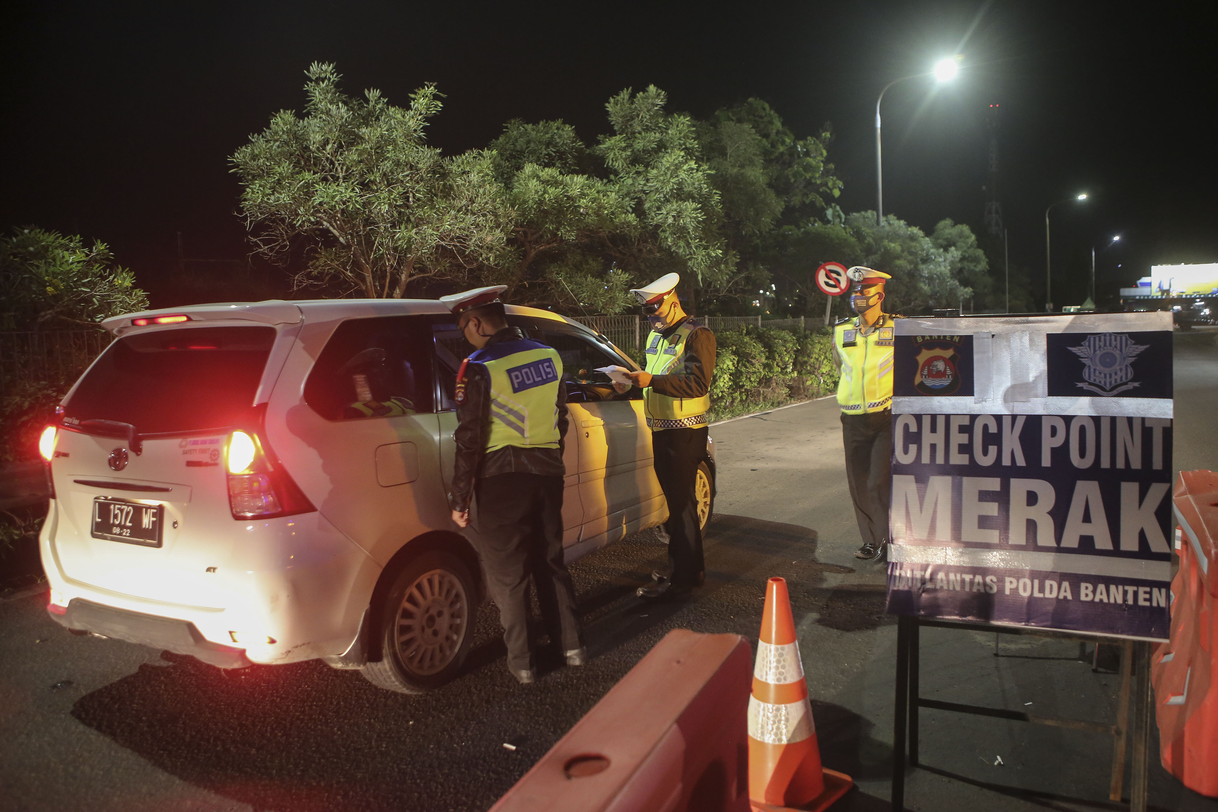 Polisi melakukan pemeriksaan surat-surat dan barang bawaan milik penumpang kendaraan pribadi dan umum melintasi gerbang tol Merak, Banten