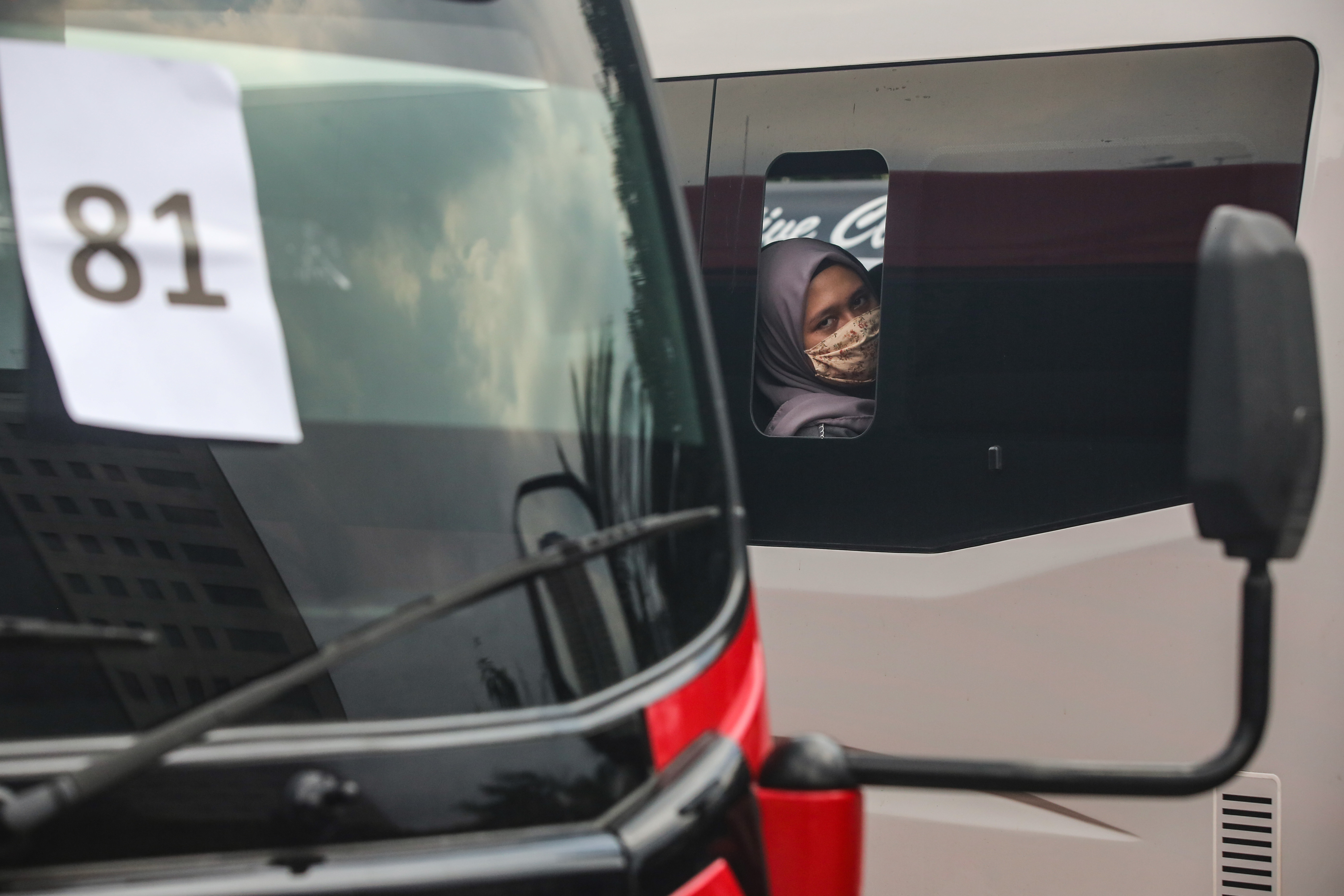 Penumpang travel yang terjaring dalam operasi penyekatan beristirahat di area penyitaan barang bukti halaman Polda Metro Jaya, Jakarta.