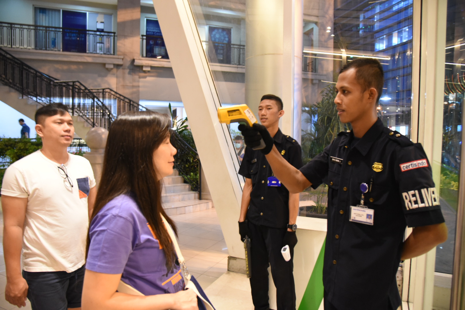 Petugas memeriksa suhu tubuh pengunjung yang hendak menyambangi Mall Central Park di Jakarta.