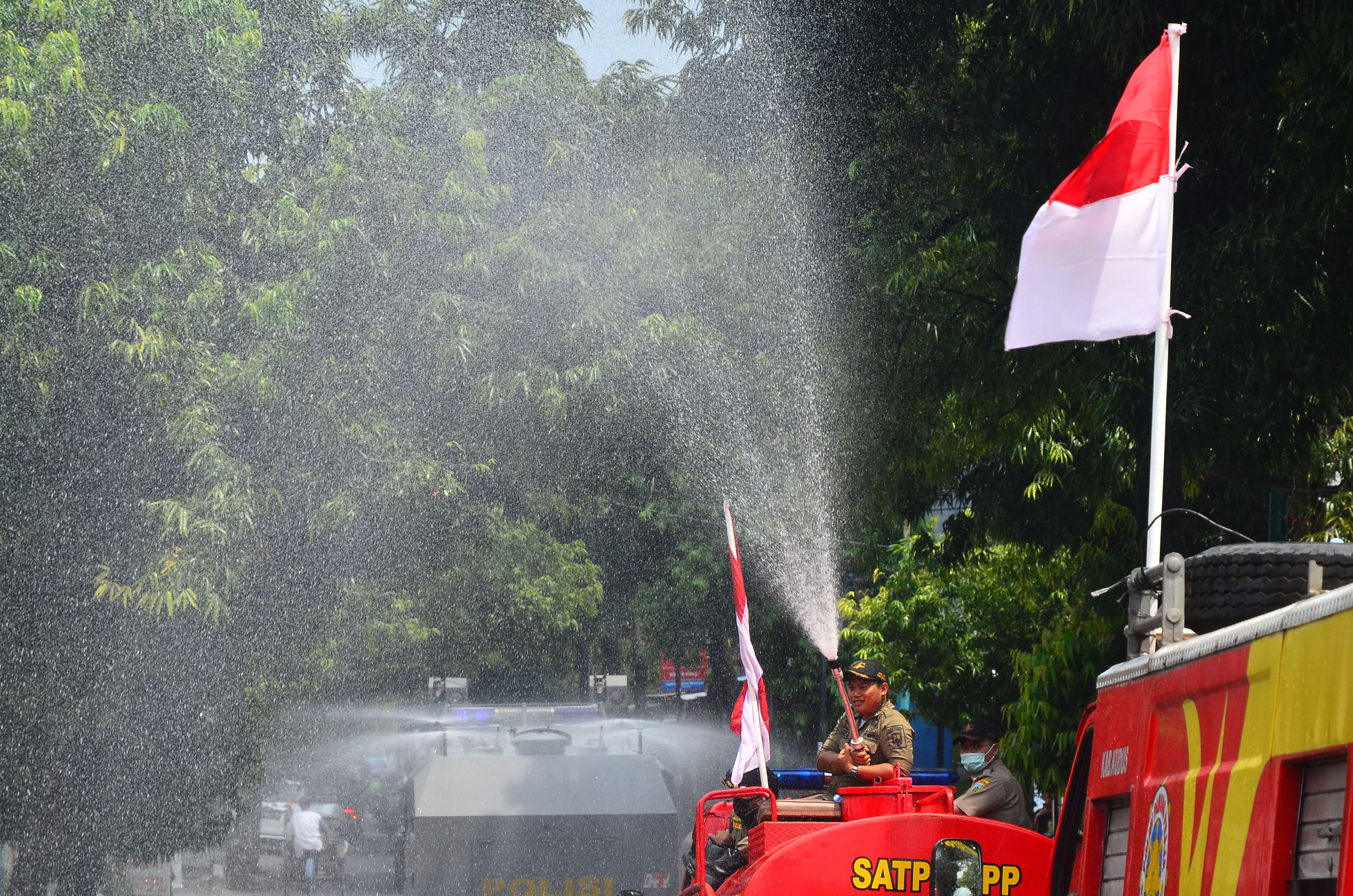 Ilustrasi petugas menyemprot cairan disinfektan di jalan untuk mencegah penyebaran covid-19.