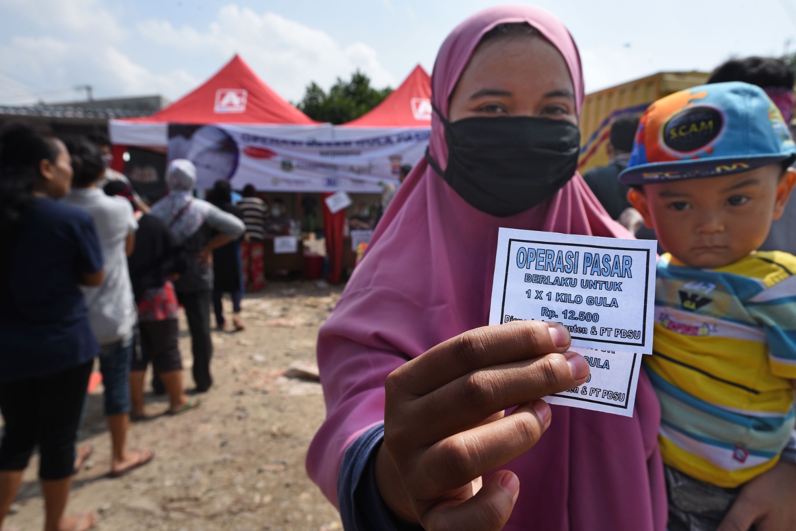 Warga memperlihatkan kupon saat antre untuk membeli gula pasir pada Operasi Pasar di Pasar Kranggot, Cilegon, Banten.