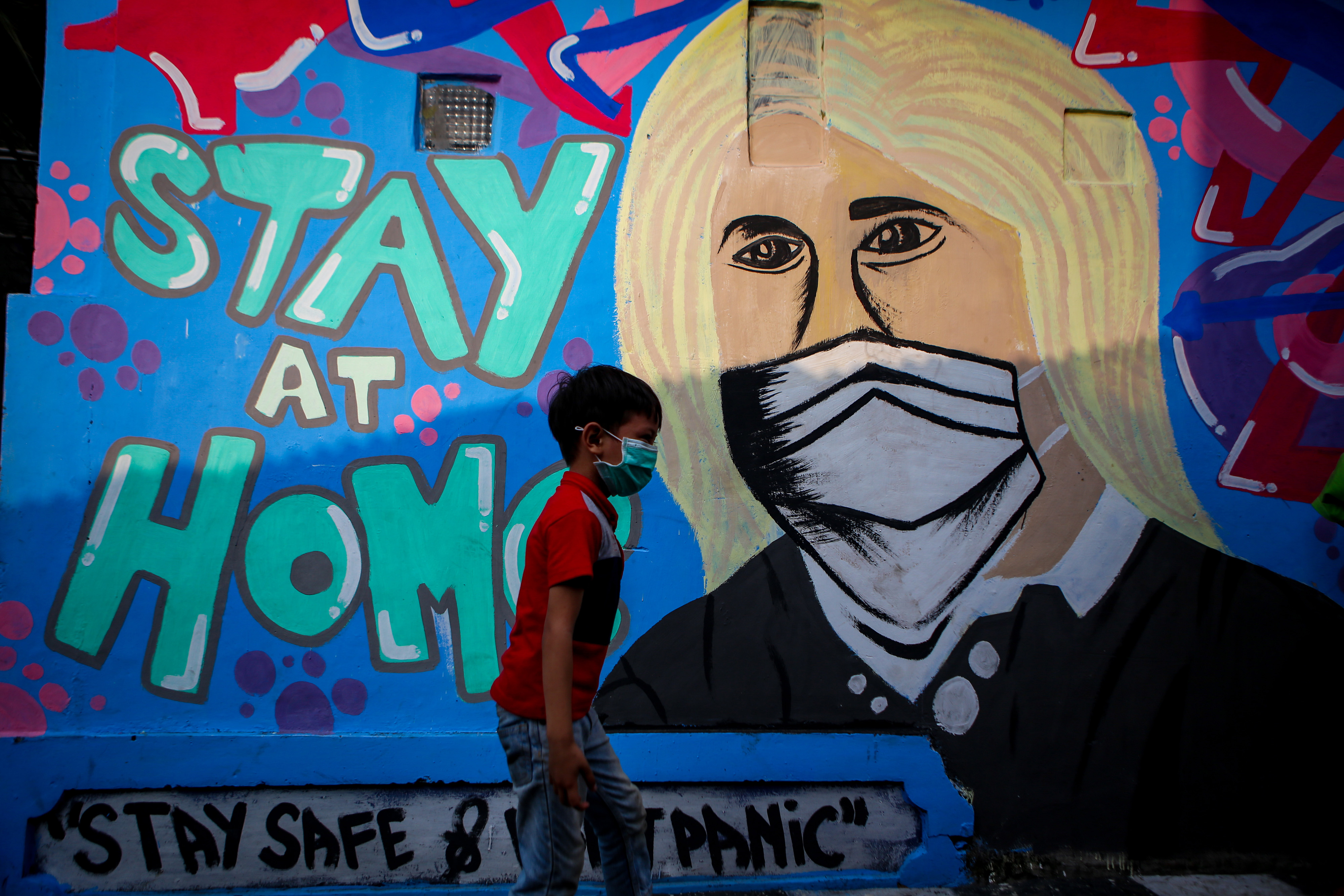 Seorang warga melintasi mural tentang covid-19 di Kampung Pinkli, Kota Tangerang, Banten.