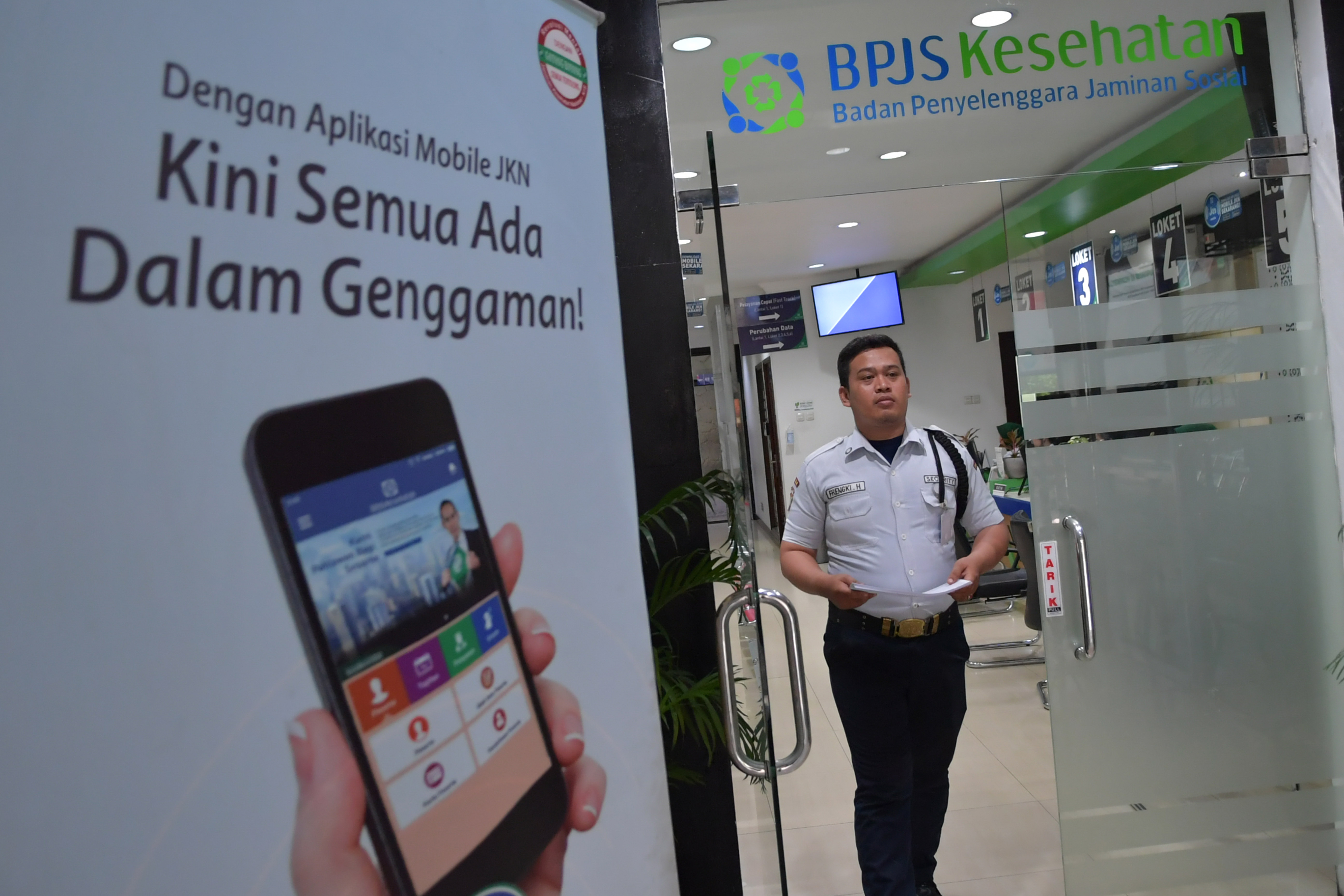  Petugas keamanan berjalan dengan membawa berkas di Kantor Pelayanan Kantor BPJS Kesehatan Jakarta Pusat, Senin (9/3).