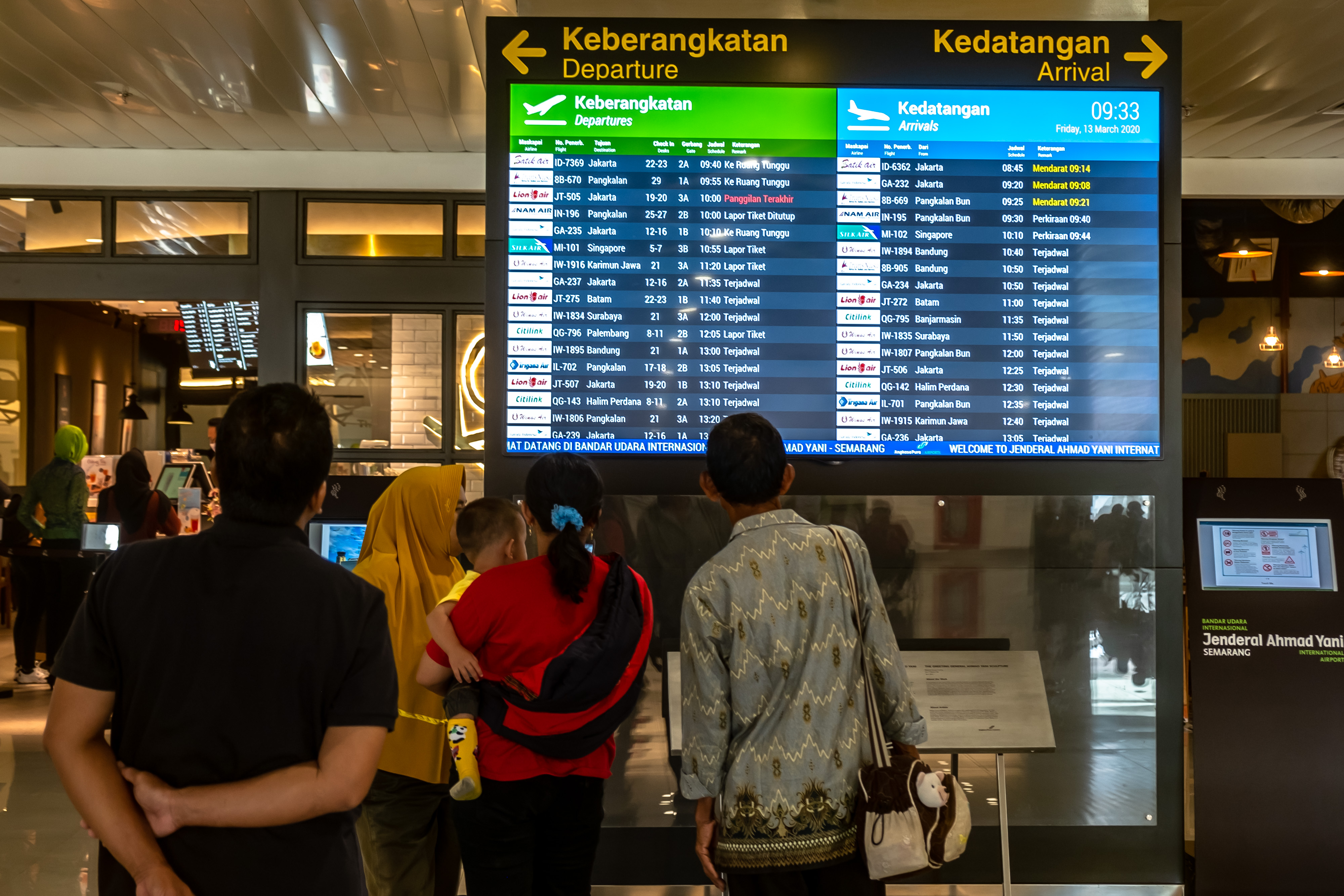 Penumpang mengamati layar informasi kedatangan dan keberangkatan pesawat di Bandara Internasional Jenderal Ahmad Yani Semarang.