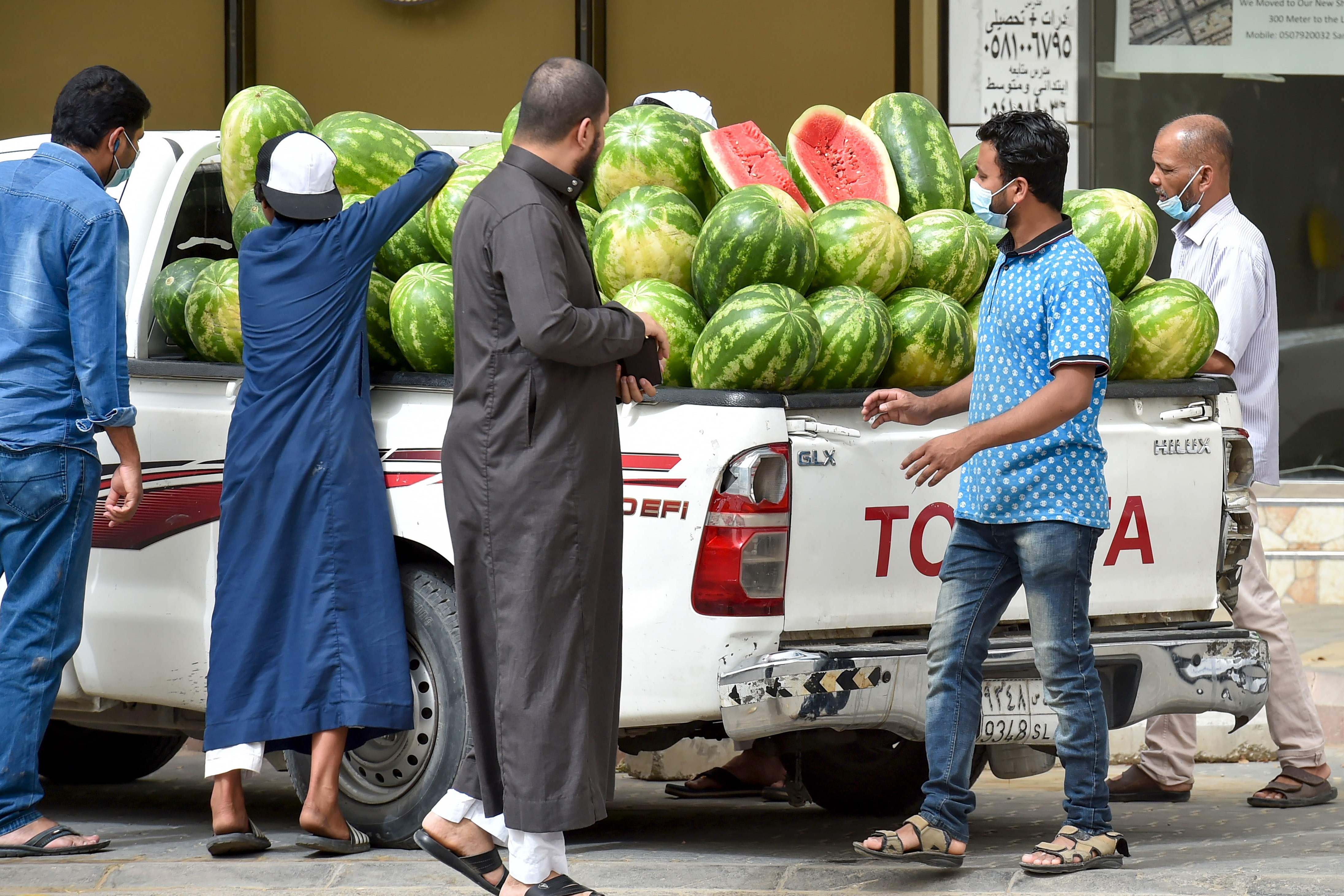 Warga mengenakan masker saat membeli semangka di Riyadh setelah pengurangan pembatasan di saat jam malam.