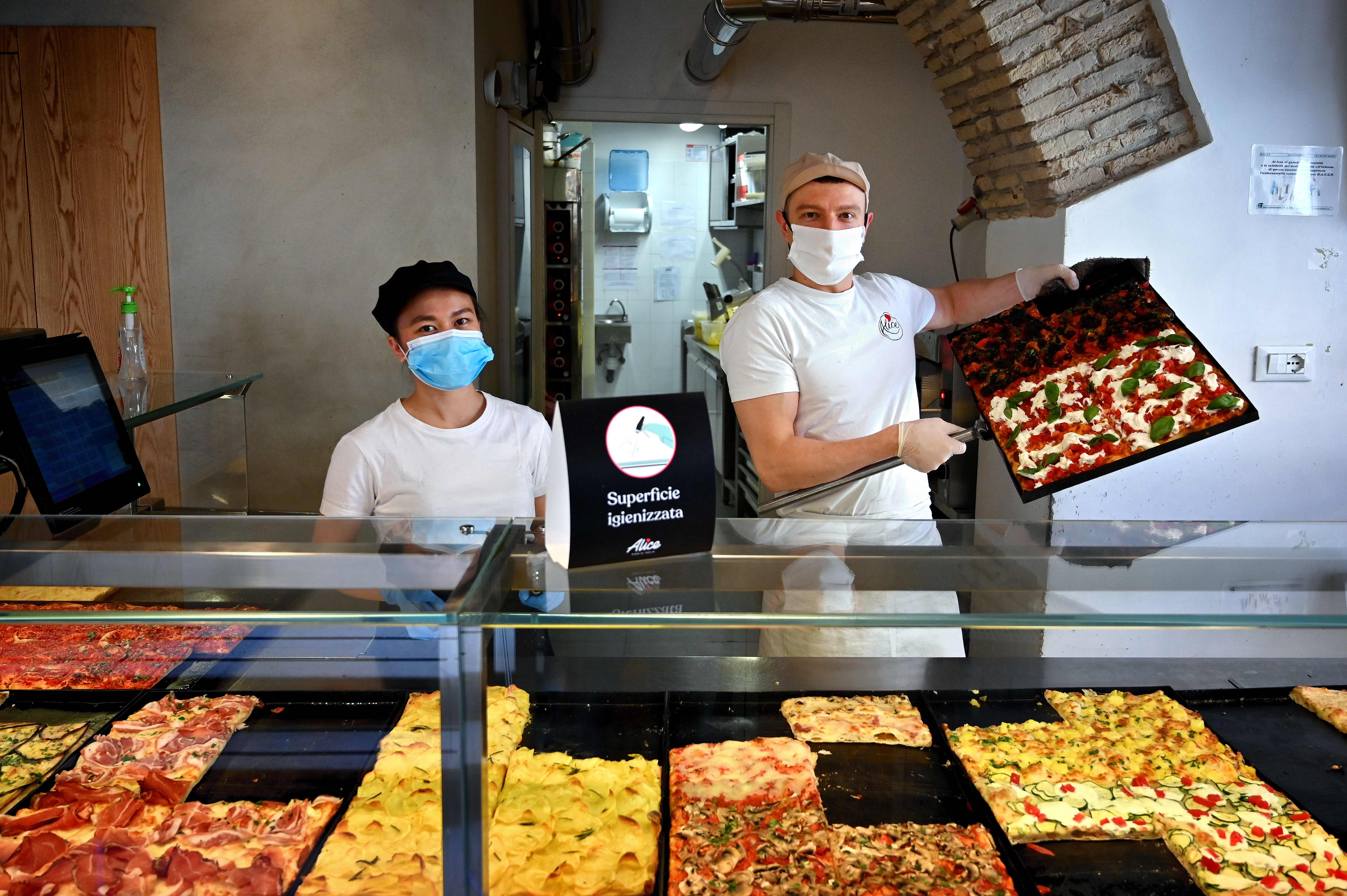 Dua pekerja toko piza berpose di Roma, Italia.