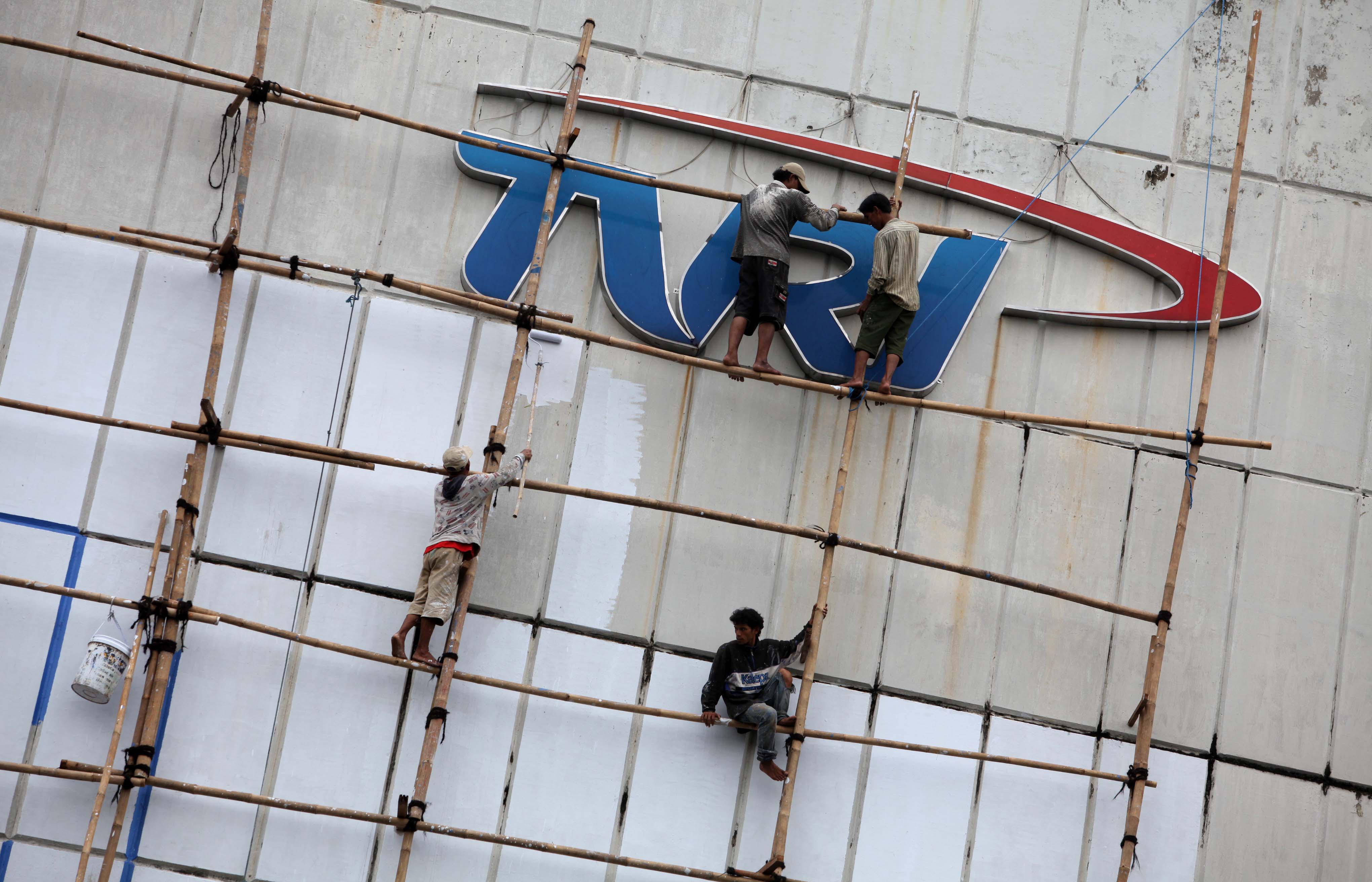Perkerja mengecat tembok di dekat logo TVRI yang terpasang di gedung Stasiun TVRI, Jakarta.