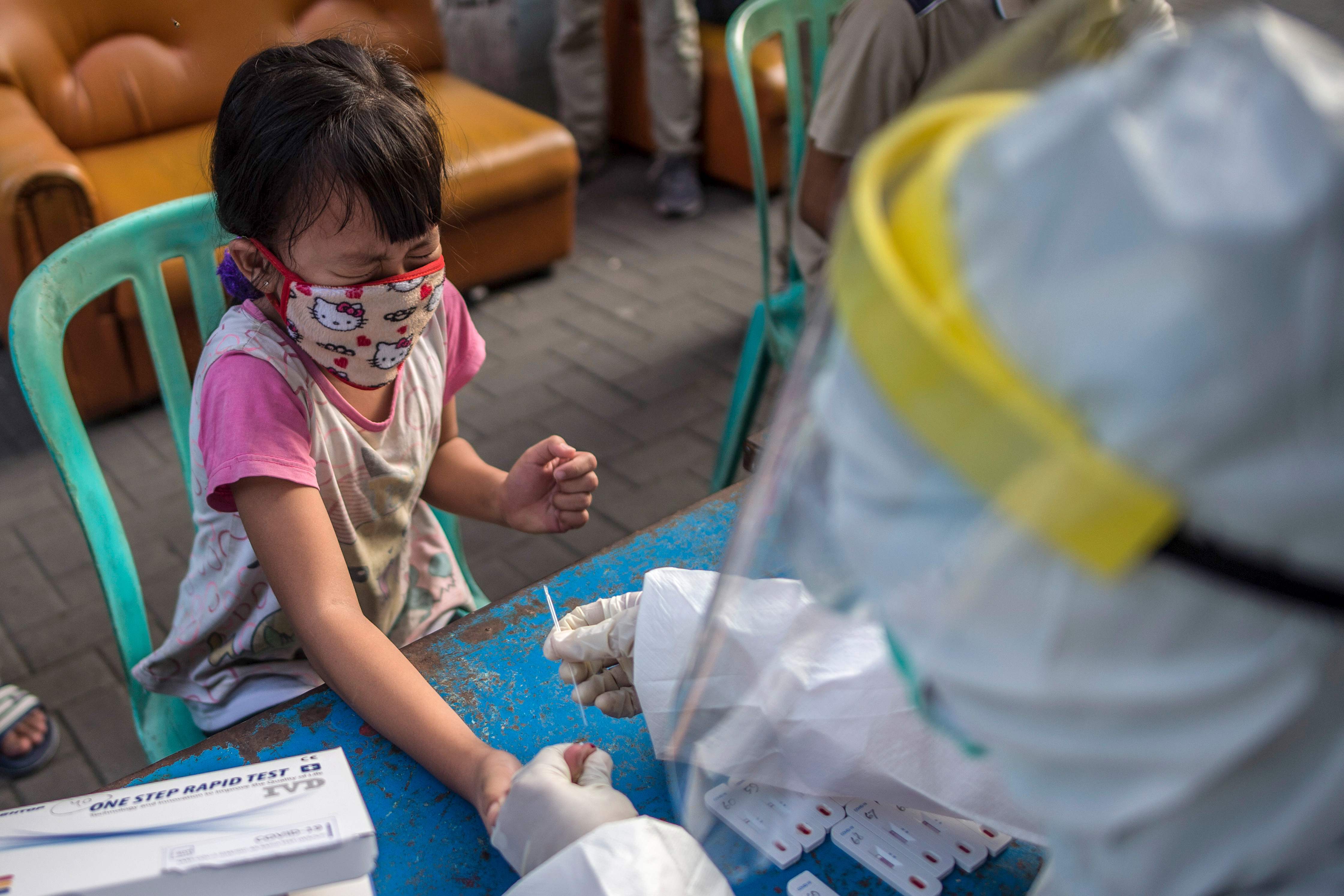 Tenaga medis mengambil sampel dari seorang anak perempuan dalam rapid test covid-19 di Surabaya, Rabu (13/5).