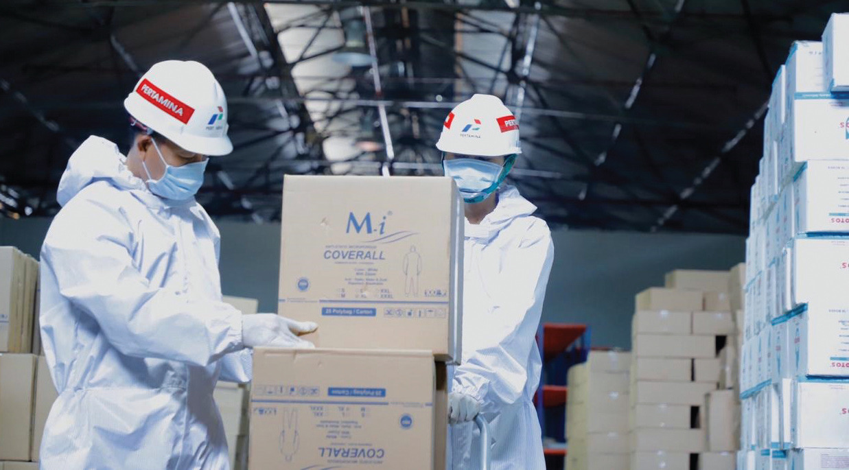 Dua petugas di gudang pertamina inventory & distribution shipping sedang mengangkut bantuan alat pelindung diri (APD) untuk didistribusikan/