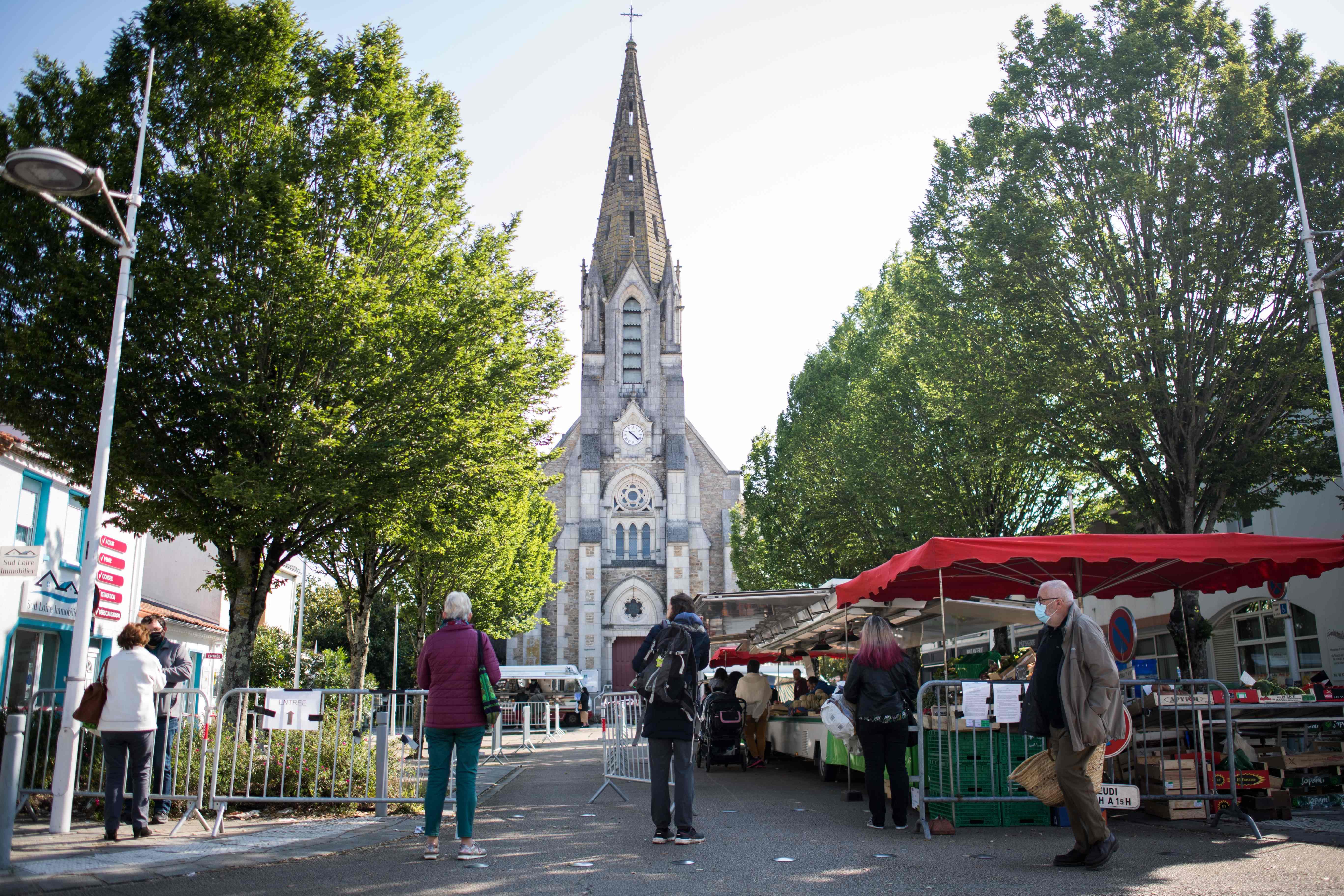 Warga menjaga jarak amansaat antre  untuk memasuki pasar di Les Sorinieres, di luar Nantes pada 14 Mei 2020