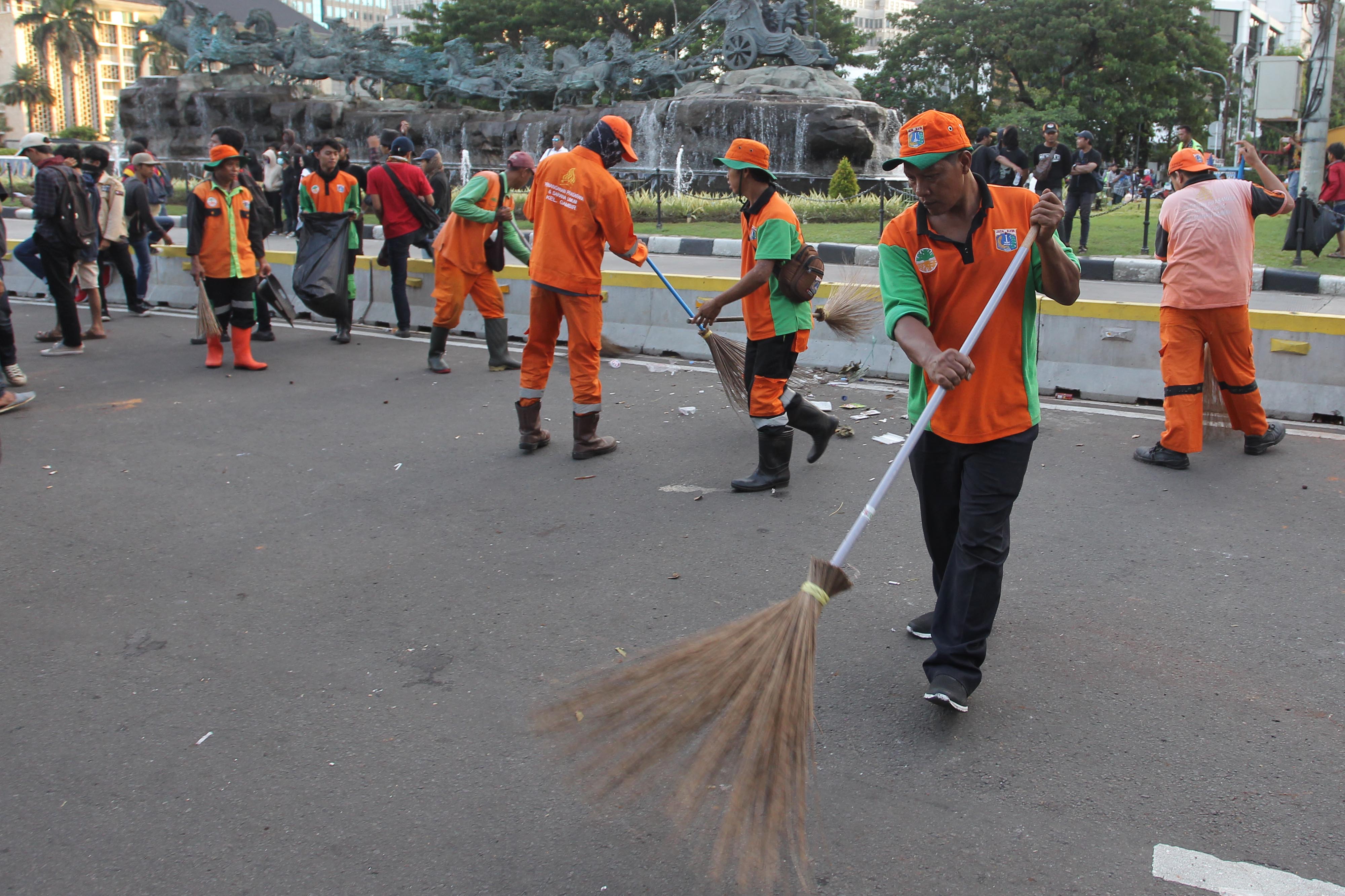 Petugas dari Suku Dinas Lingkungan Hidup Kota Administrasi Jakarta Pusat membersihkan sampah  seusai aksi massa buruh