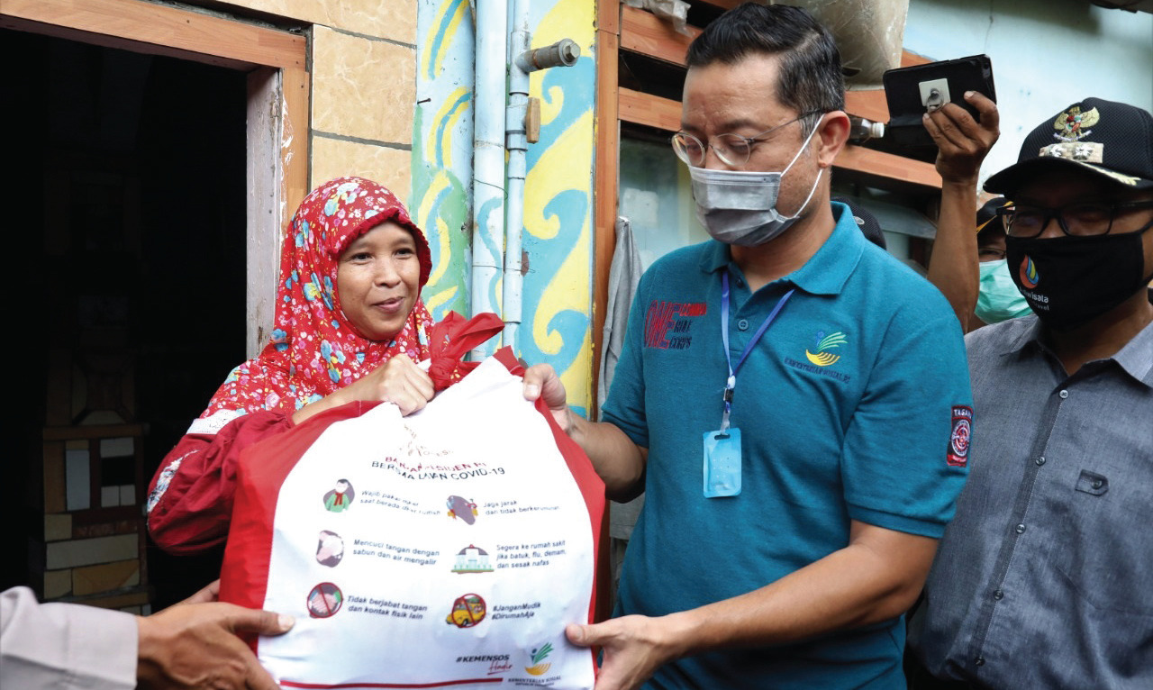 Mensos Juliari P Batubara (Tengah) membagikan Bantuan kepada salah satu warga.