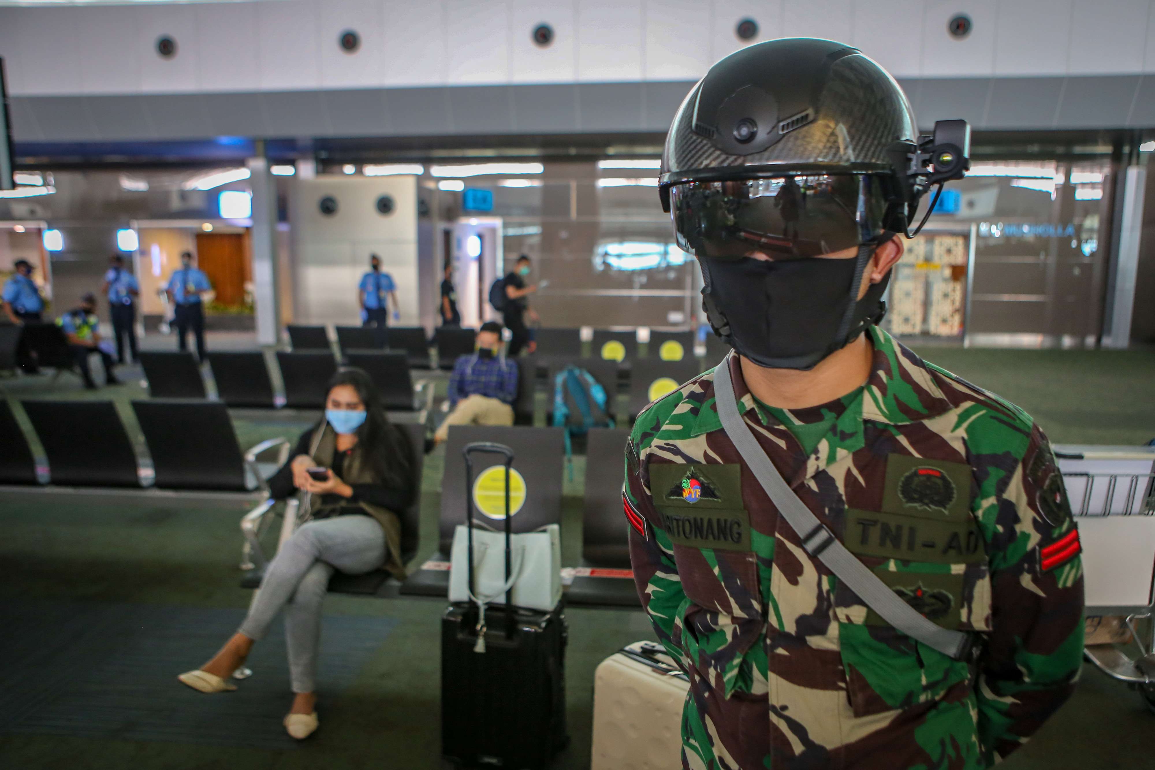 Personel TNI menggunakan helm pendeteksi suhu tubuh di Terminal 3 Bandara Internasional Soekarno Hatta, Tangerang, Banten