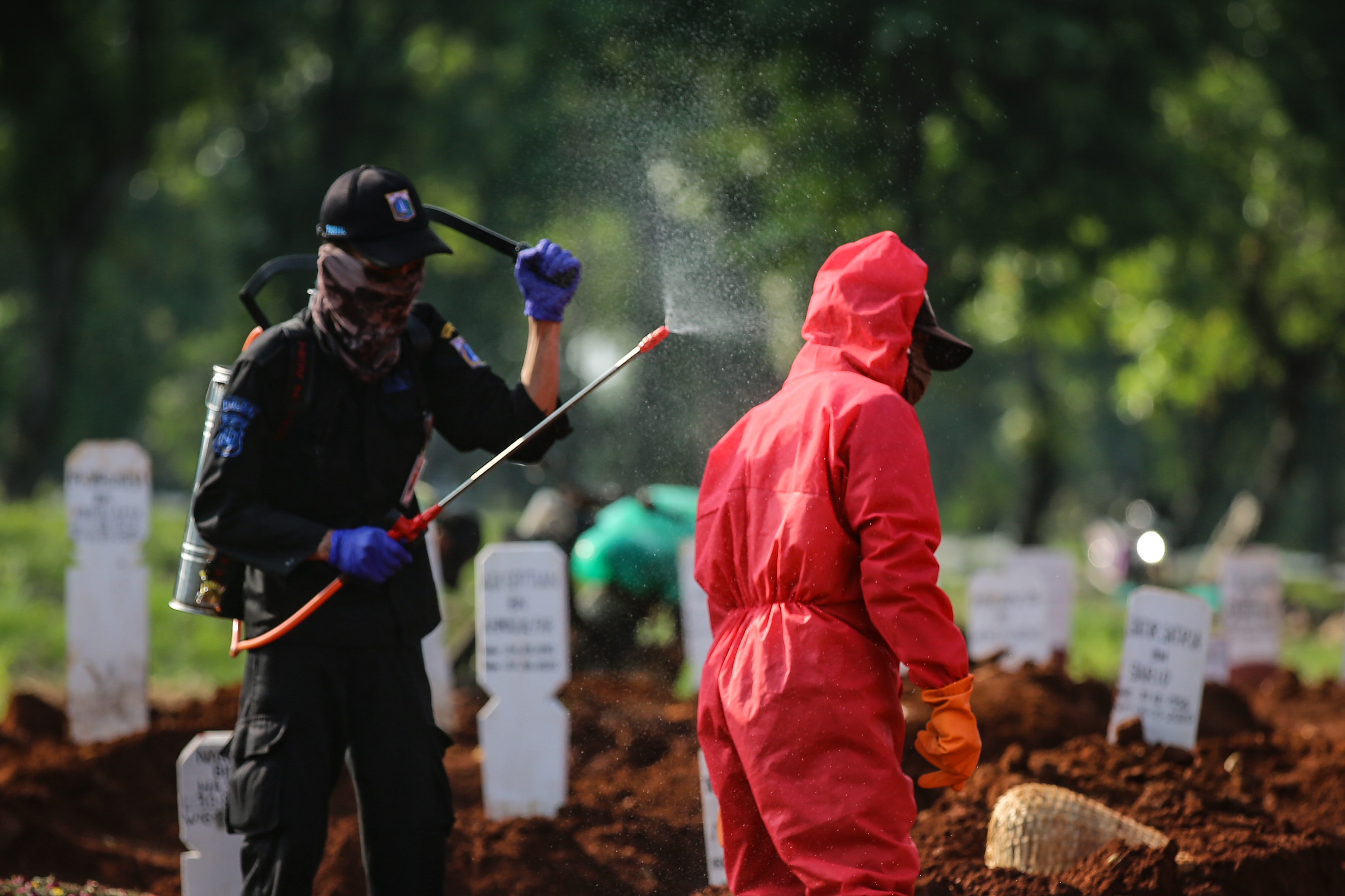 Petugas pemakaman disemprot cairan disinfektan seusai memakamkan jenazah covid-19 di TPU Pondok Ranggon, Jakarta, Kamis (7/5/2020)