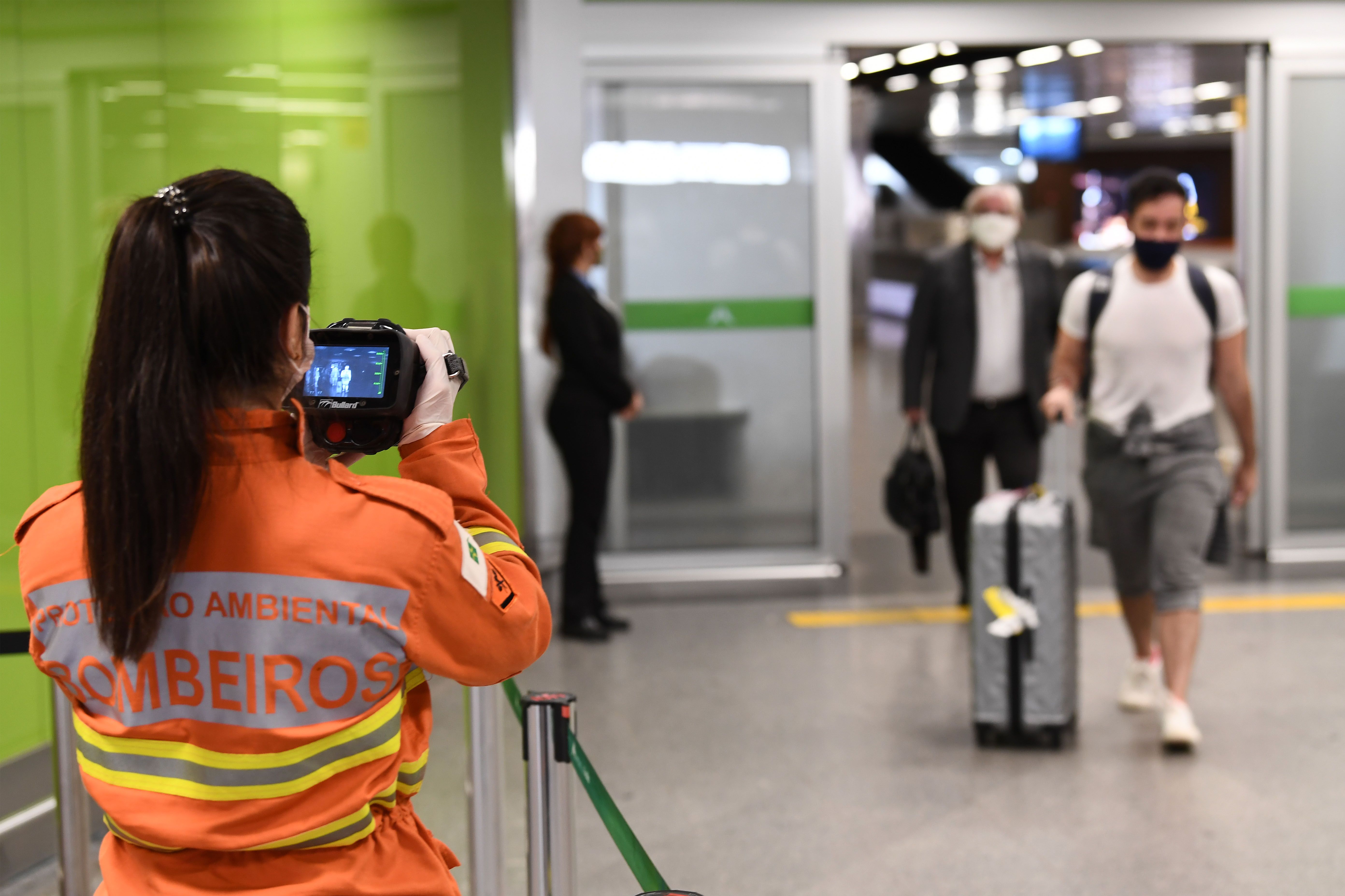 Petugas memeriksa suhu calon penumpang di bandara Brasil.
