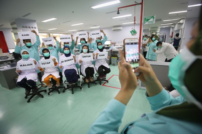 Petugas medis melakukan foto dengan memegang tulisan 