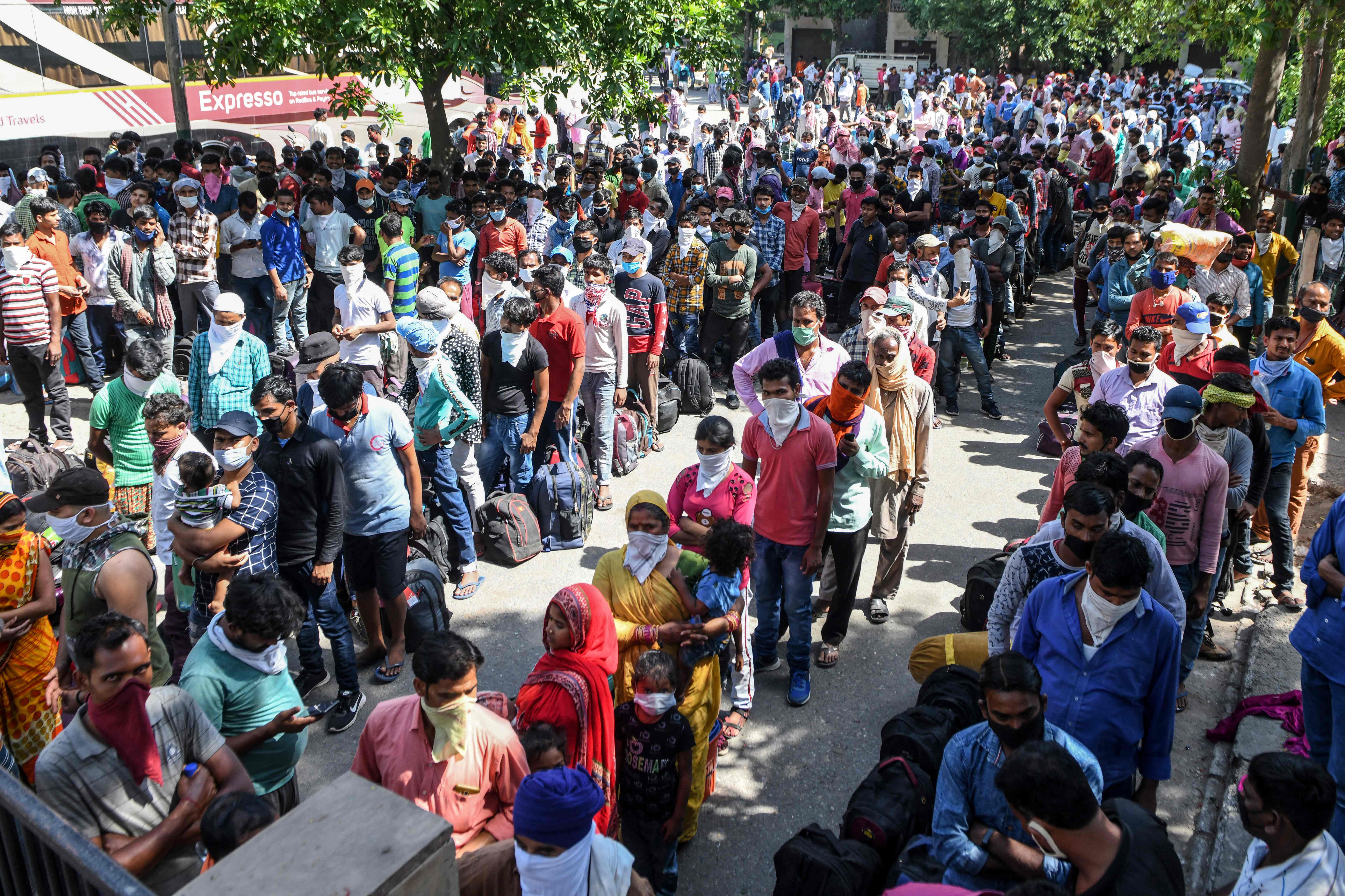Pekerja migran menunggu diperiksa suhu tubuhnya sebelum diizinkan naik kereta di Kota Amritsar, India.