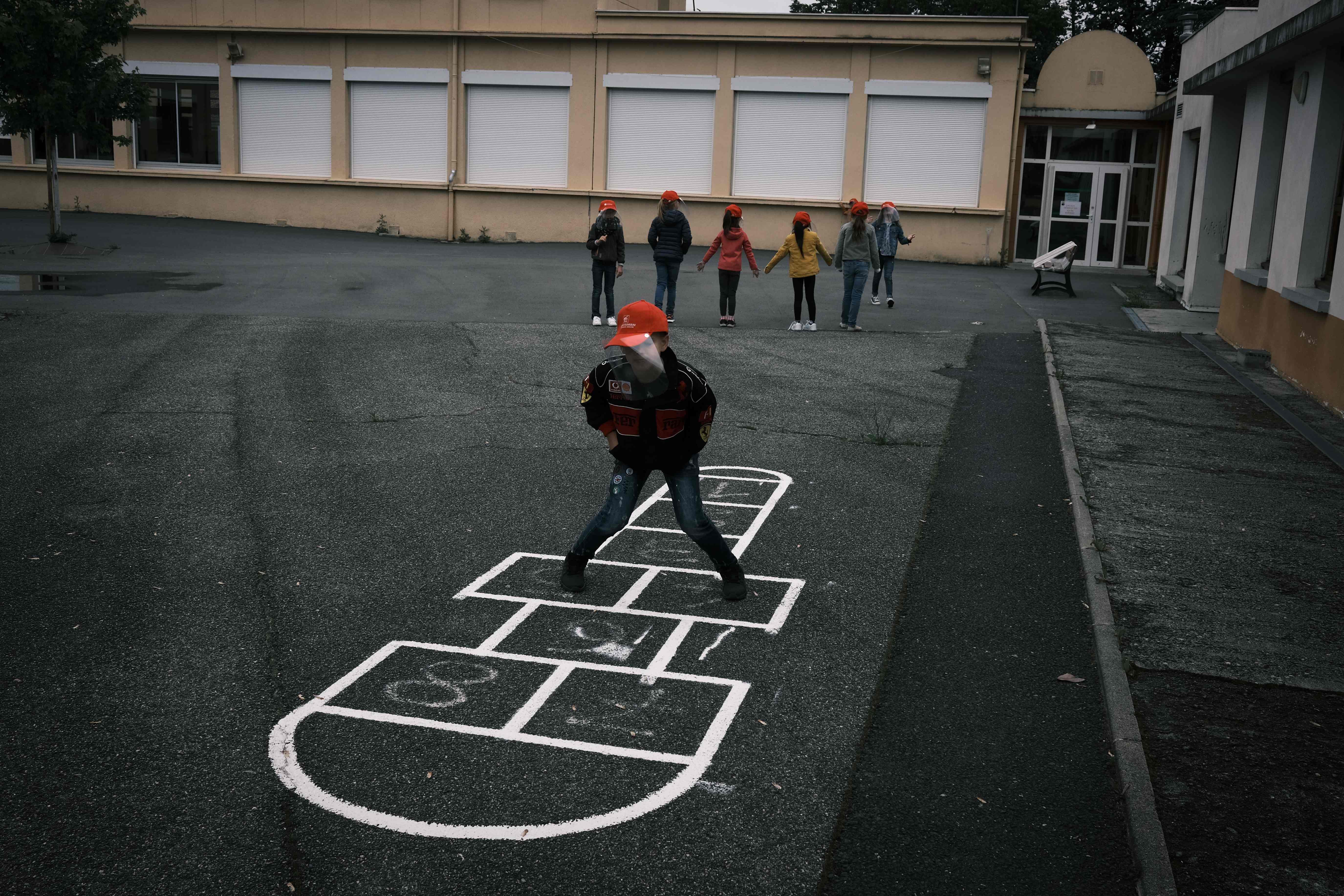 Seorang anak bermain di halaman sekolah yang telah dibuka kembali di La Grand-Croix, Prancis, Selasa (12/5).