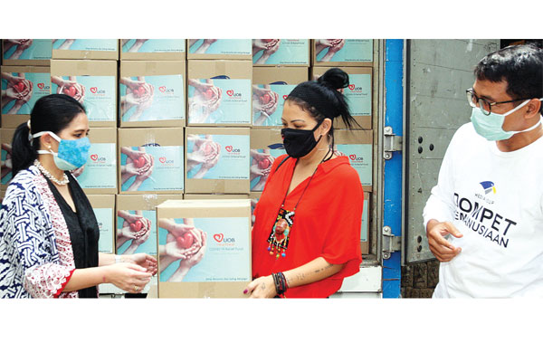 Head of Corporate Communication UOB Indonesia, Maya Rizano (kiri), secara simbolis menyerahkan paket sembako kepada pendiri Rumah Harapan,  