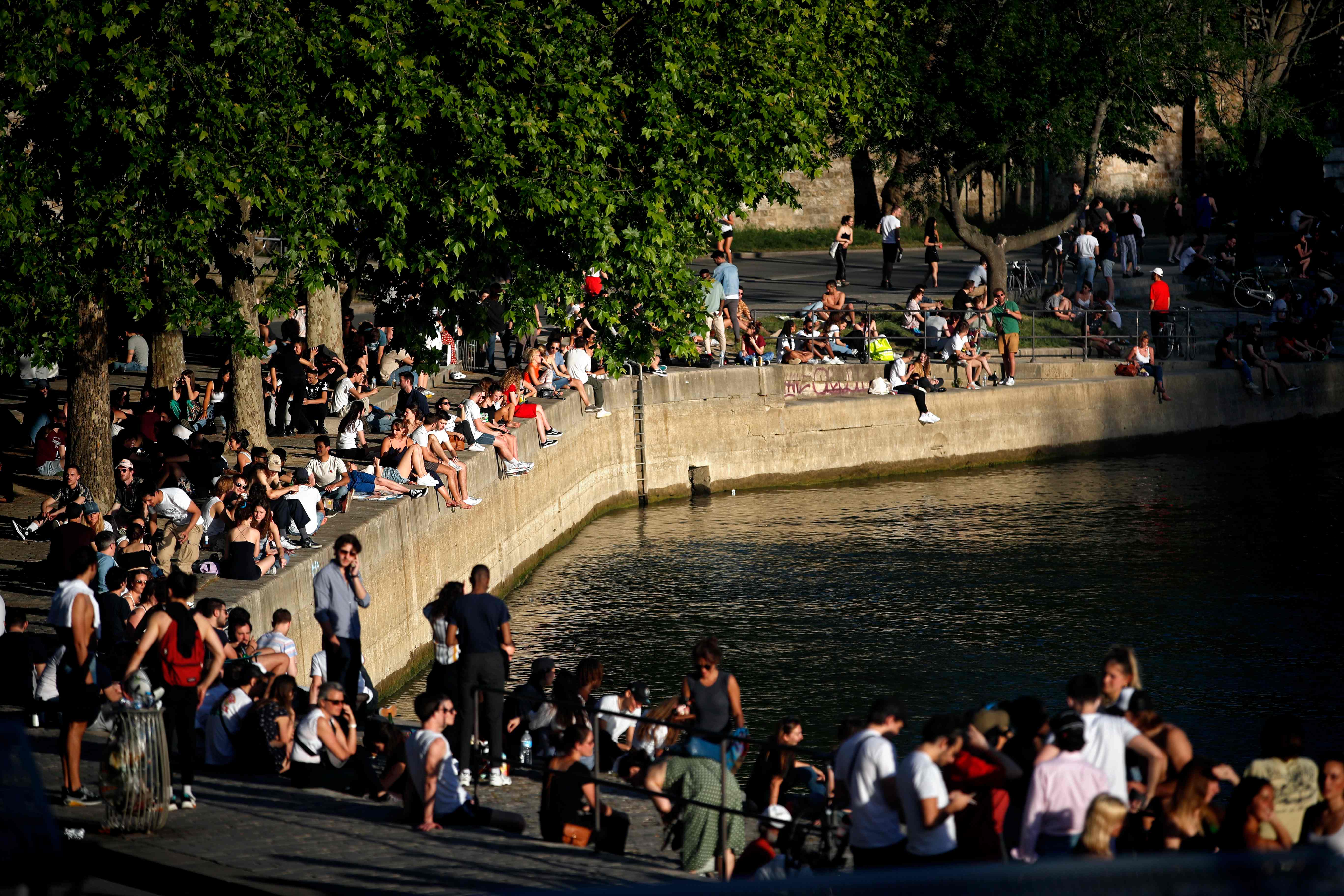 Orang-orang berkumpul dan mandi matahari di tepi sungai Seine di Paris pada 21 Mei 2020