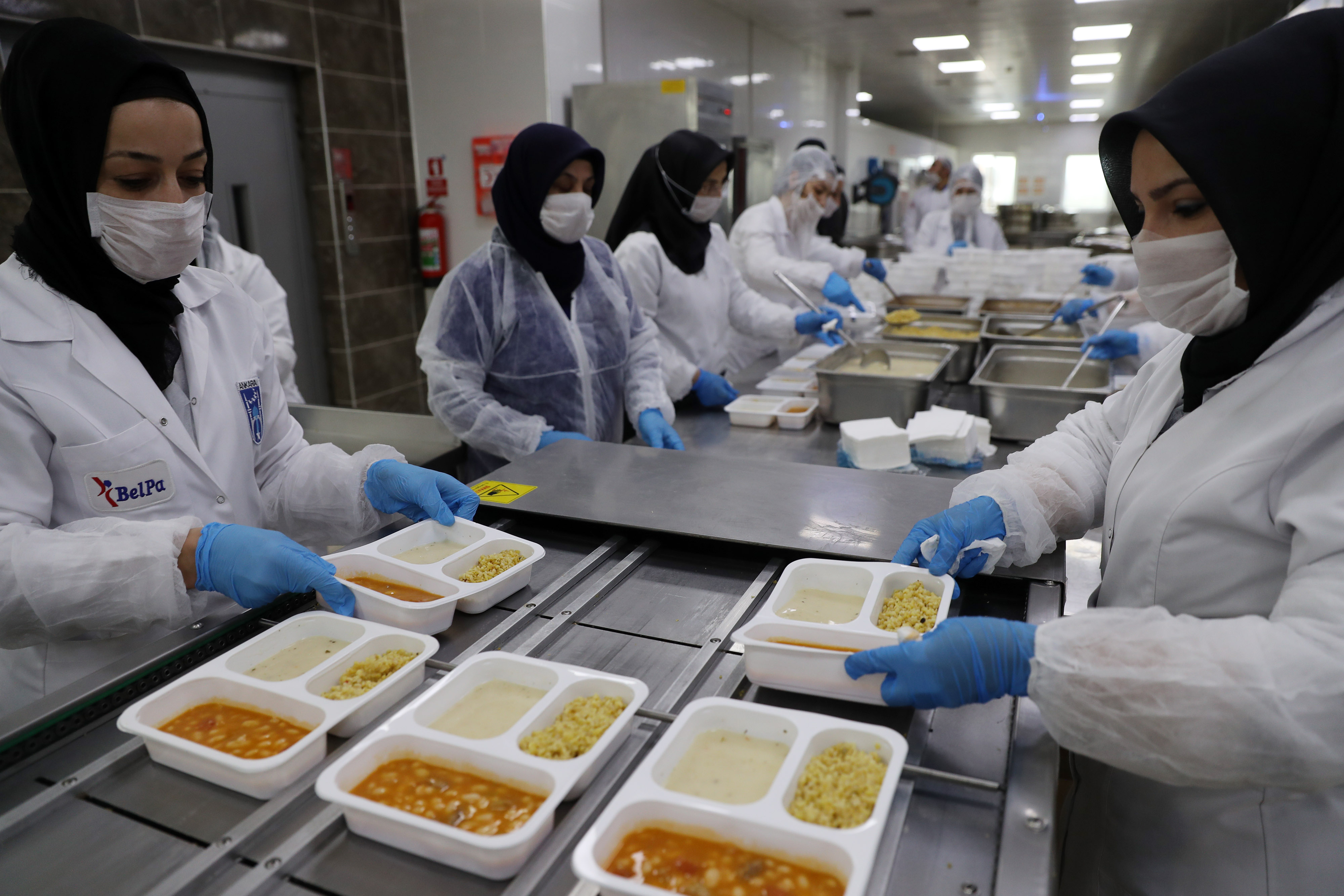 Relawan menggunakan alat pelindung diri (APD) lengkap saat menyiapkan hidangan untuk berbuka puasa di Ankara, Turki, Kamis (7/5).