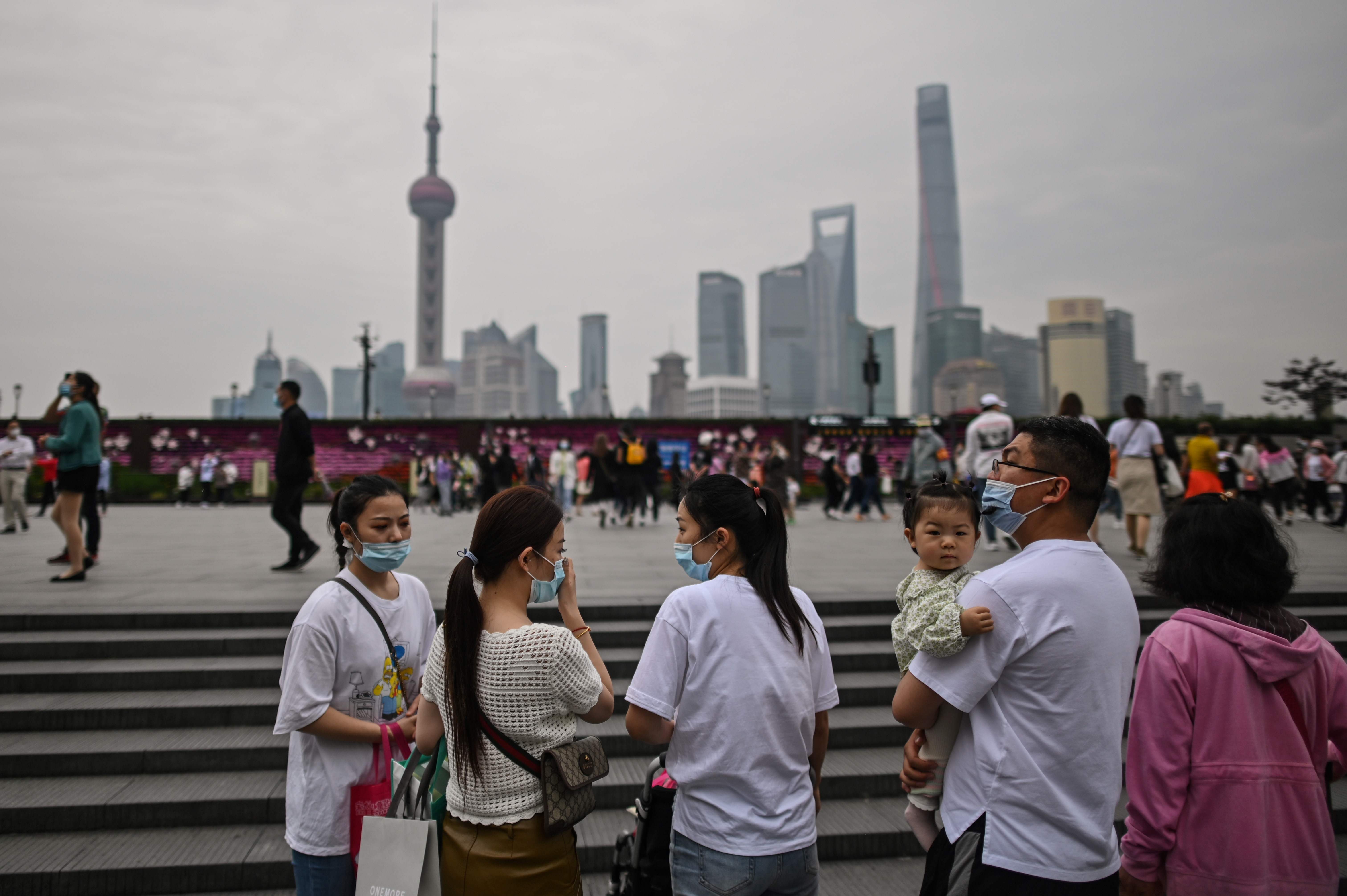 Warga Shanghai berjalan-jalan di tepi sungai Huangpu sambil memakai masker pada 1 Mei 2020 