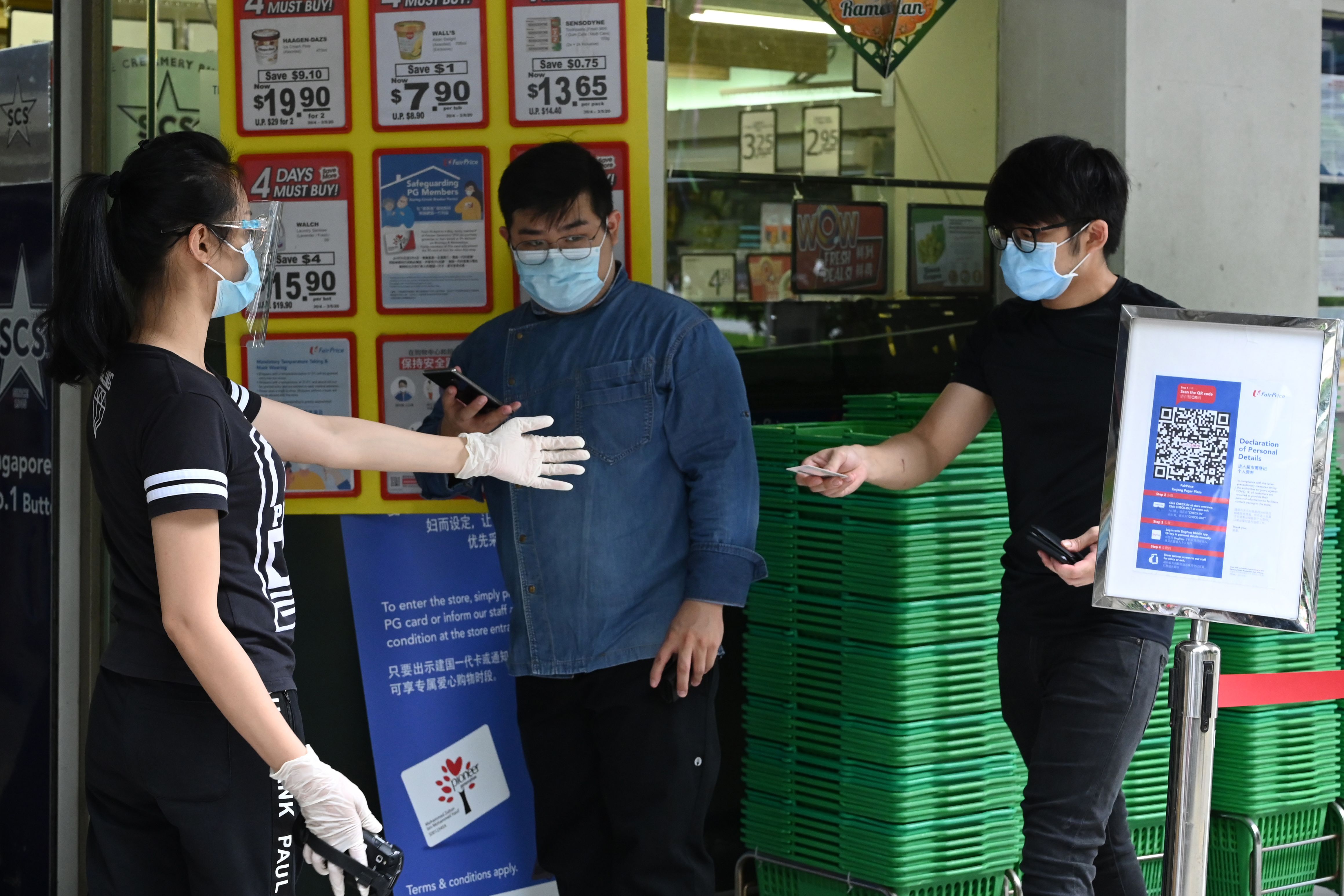 Warga Singapura memberikan KTPnya ke penjaga Supermarket sebelum bisa memasuki kawasan supermarket