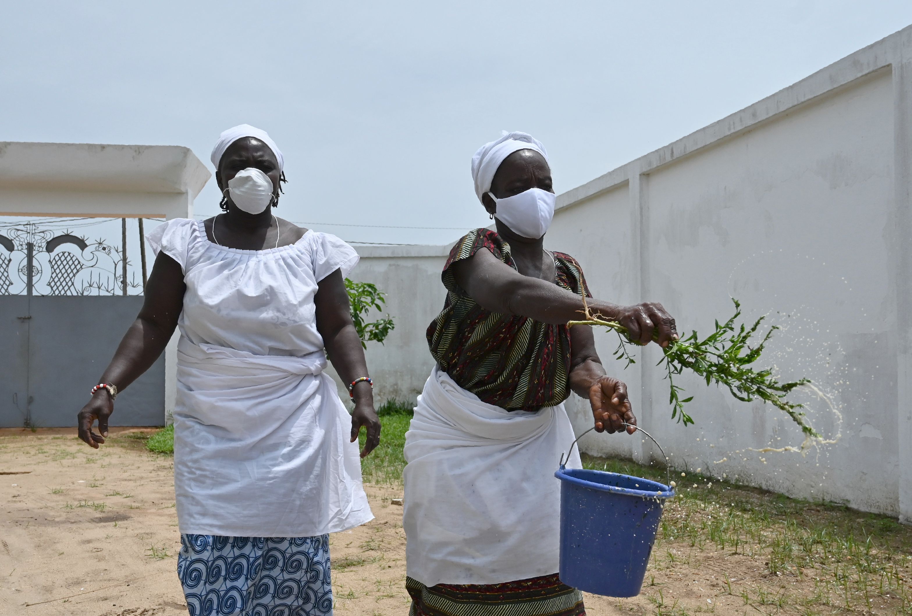 Sepasang dukun menyiramkan air untuk melindungi warga Pantai Gading dari ancaman covid-19.