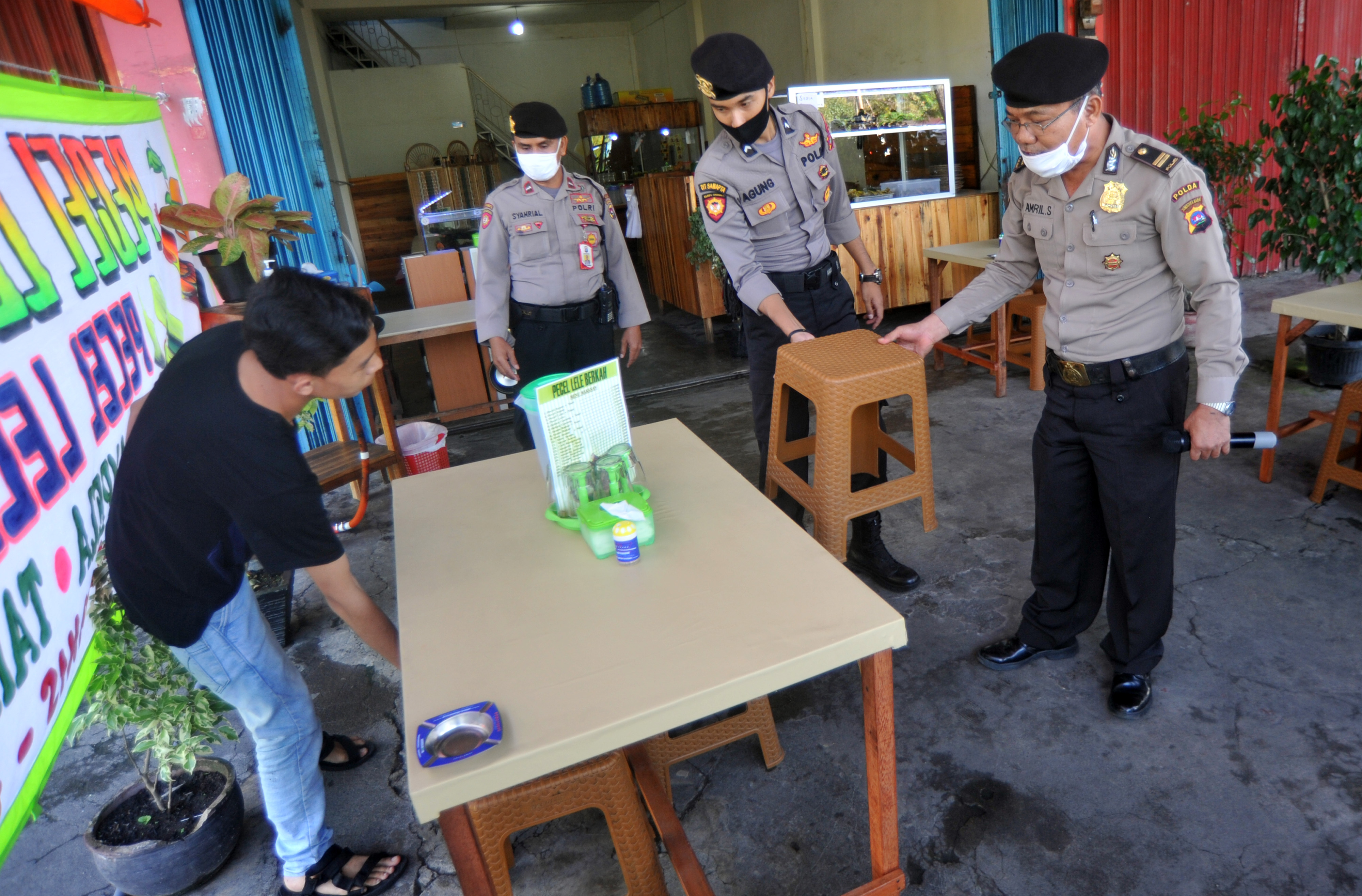 Petugas Dit Samapta Polda Sumbar mengatur kursi warung makan untuk antrean pembeli sesuai dengan aturan PSBB di Padang, Sumatra Barat.