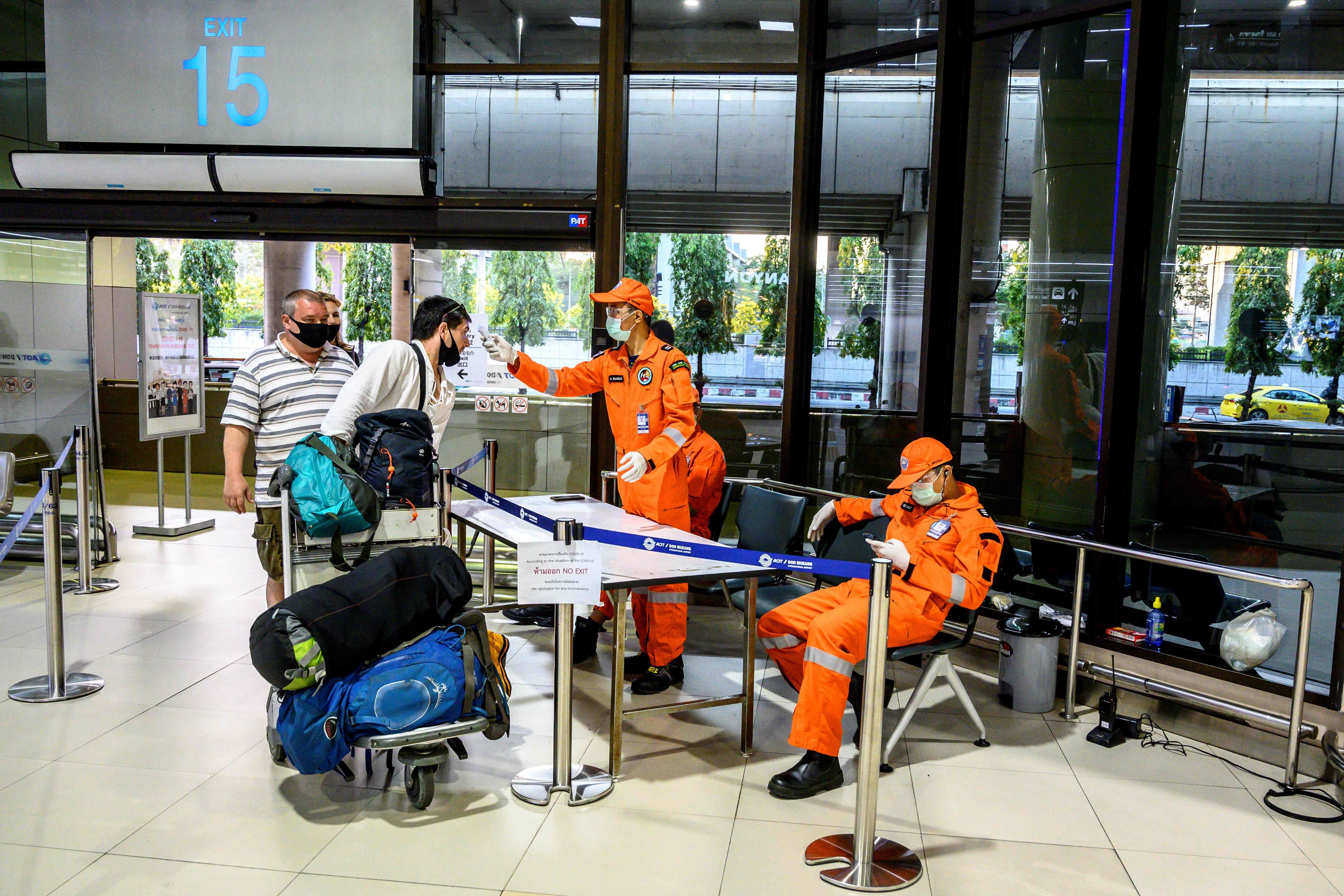 Petugas memeriksa suhu tubuh calon penumpang di Bandara Internasional Don Mueang, Bangkok, pada Maret.