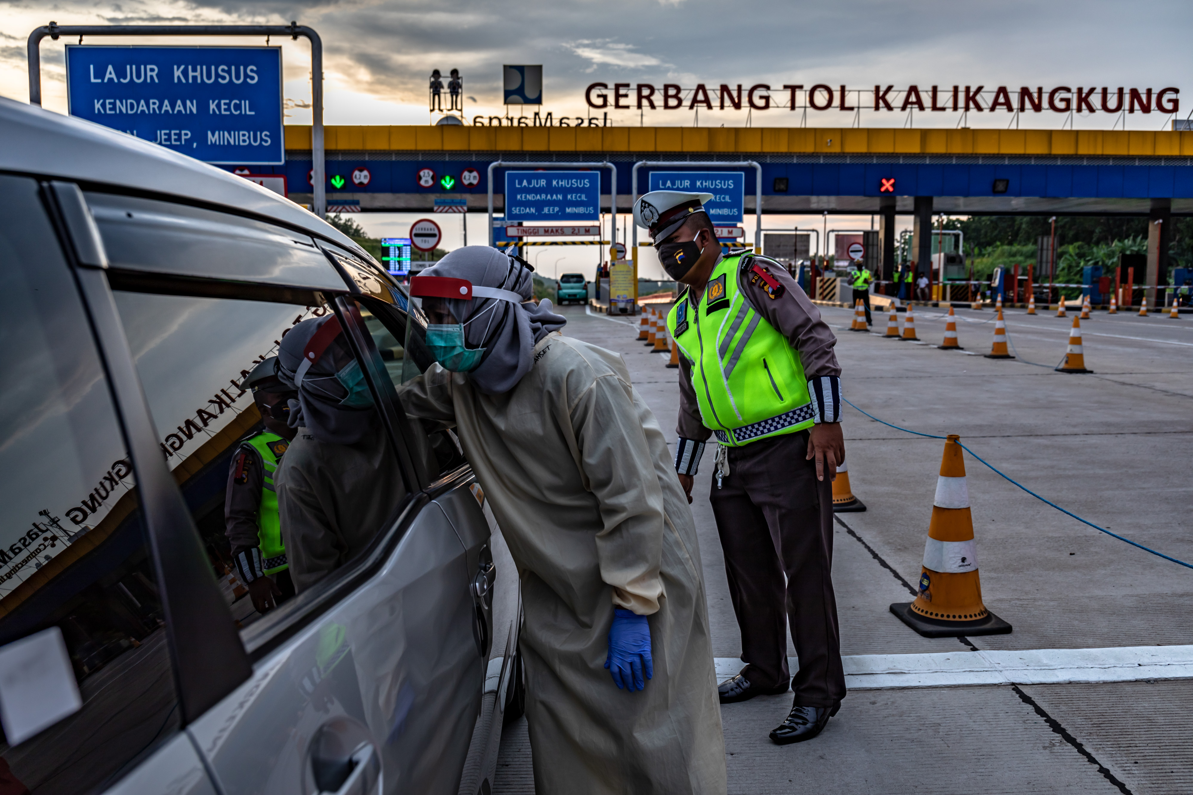 Petugas kesehatan memeriksa suhu pengendara roda empat saat penyekatan pemudik di Gerbang Tol Kalikangkung, Semarang