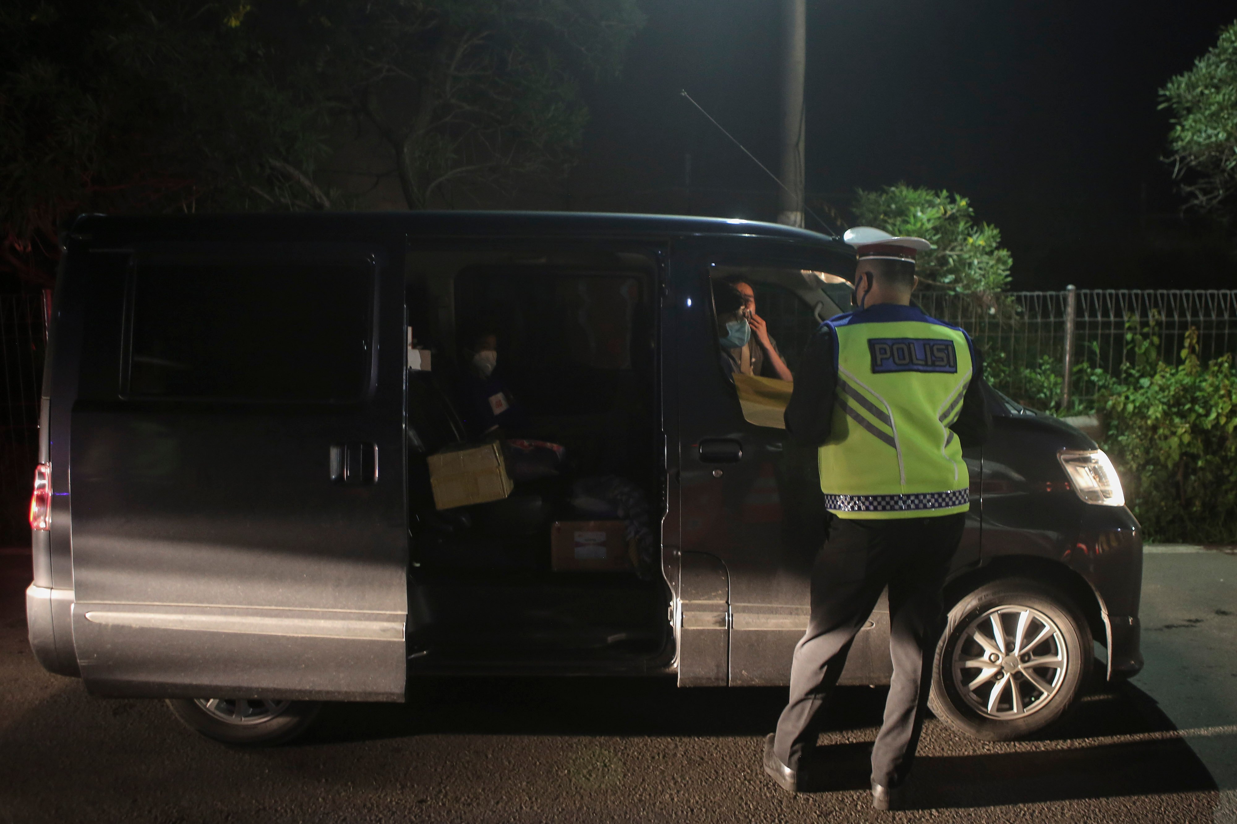 Petugas memeriksa surat dan barang bawaan kepada penumpang kendaraan di gerbang tol Merak, Banten, Kamis (21/5). 