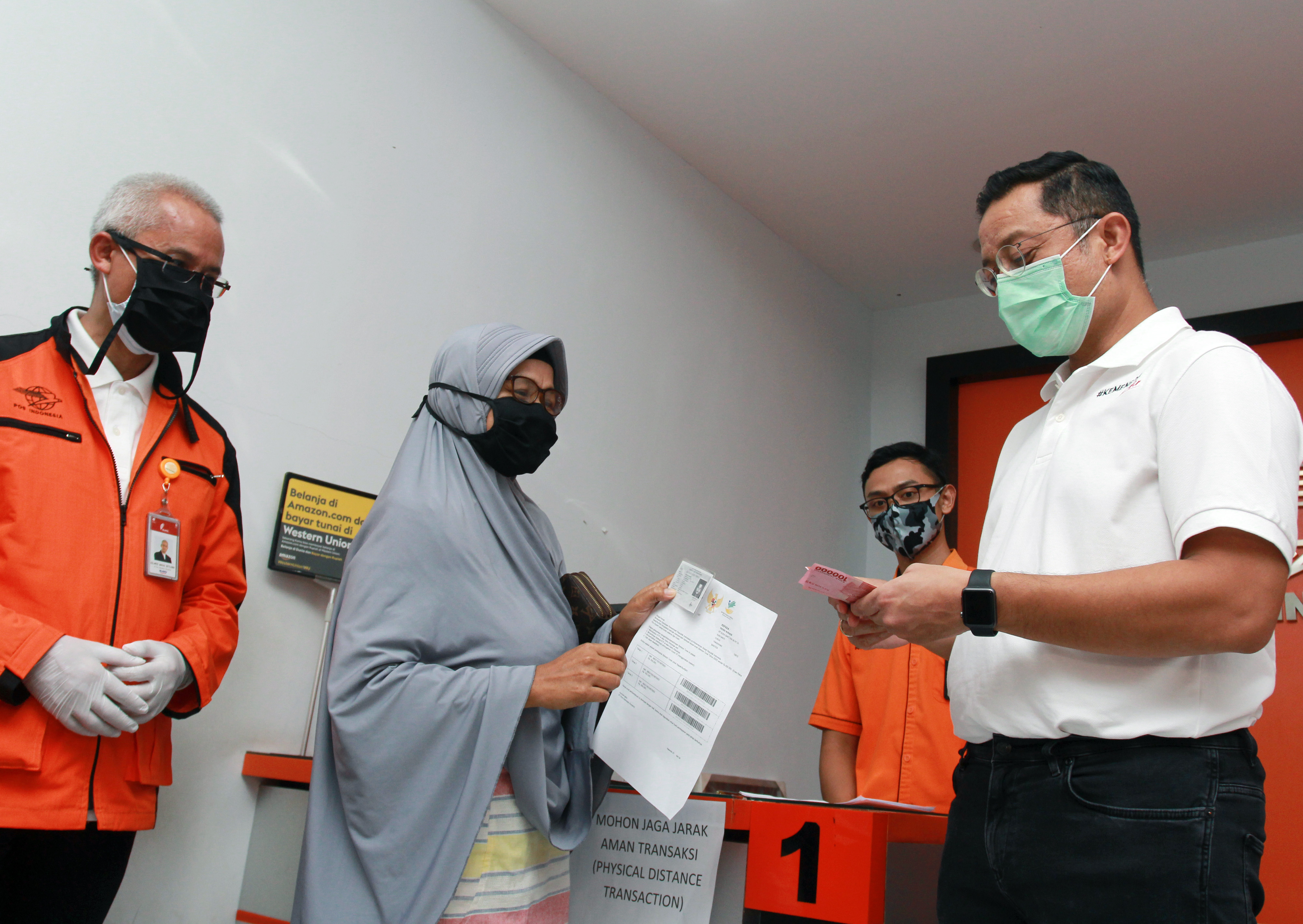 Mensos Juliari P Batubara (kanan) memberikan uang bantuan pemerintah kepada warga saat meninjau pencairan BST di Curug, Tangerang, Banten.