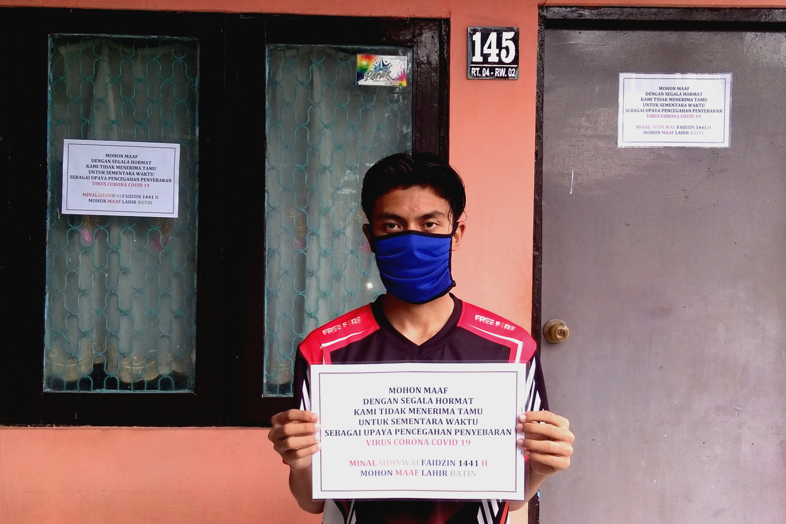 Warga Kelurahan Parteker, Kecamatan Kota, Pamekasan, Jawa Timur, menunjukkan pamflet yang berisi pesan tidak menerima tamu di rumahnya.