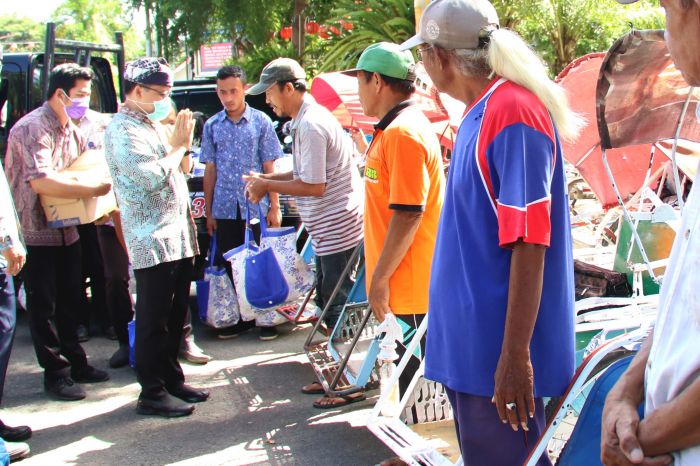 Bupati Banyuwangi Abdullah Azwar Anas (kedua kiri) memberikan bantuan sembako kepada tukang becak di Taman Sri Tanjung, Banyuwangi.