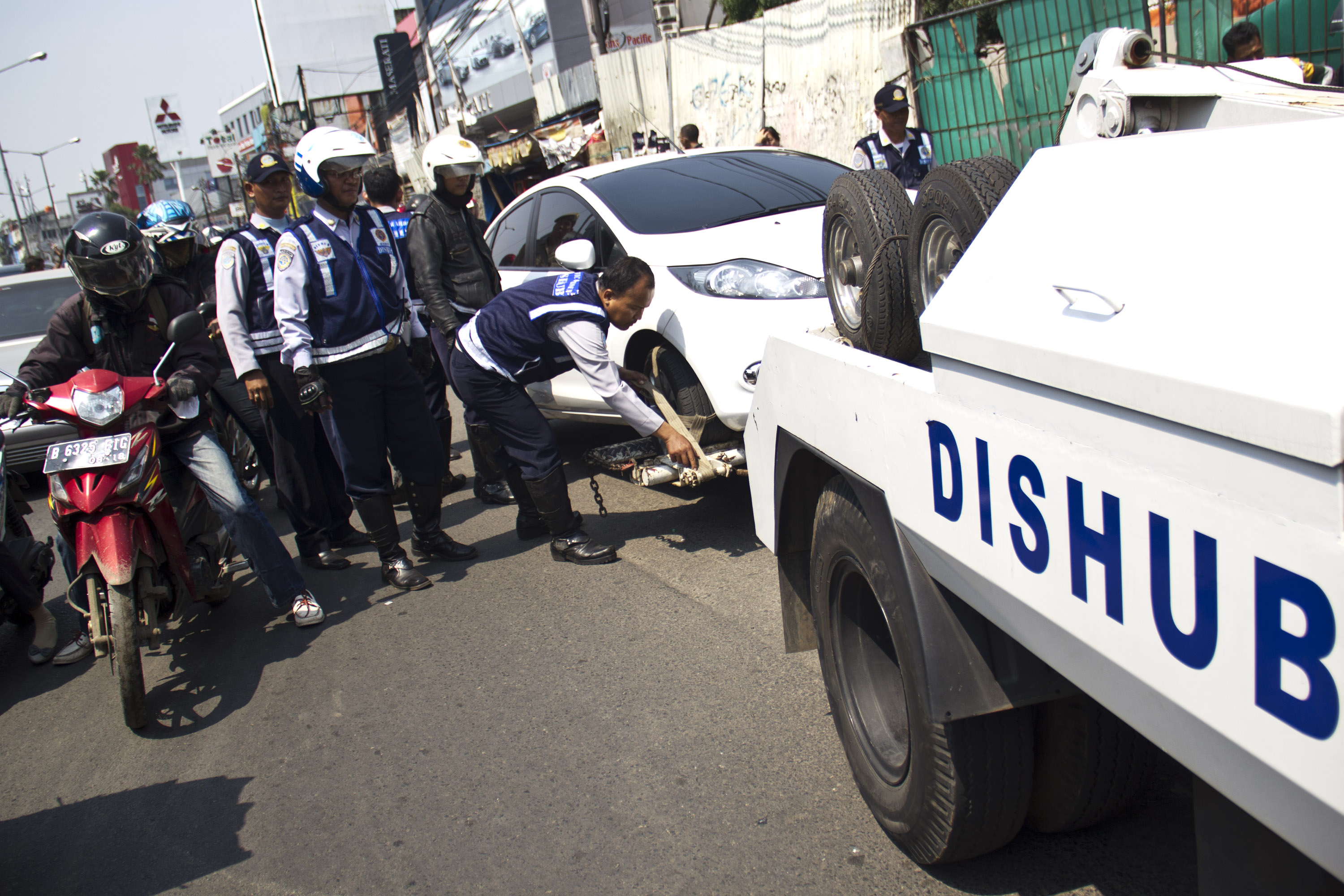 Petugas Dinas Perhubungan menderek sebuah mobil saat melakukan razia parkir liar di kawasan Jakarta Selatan